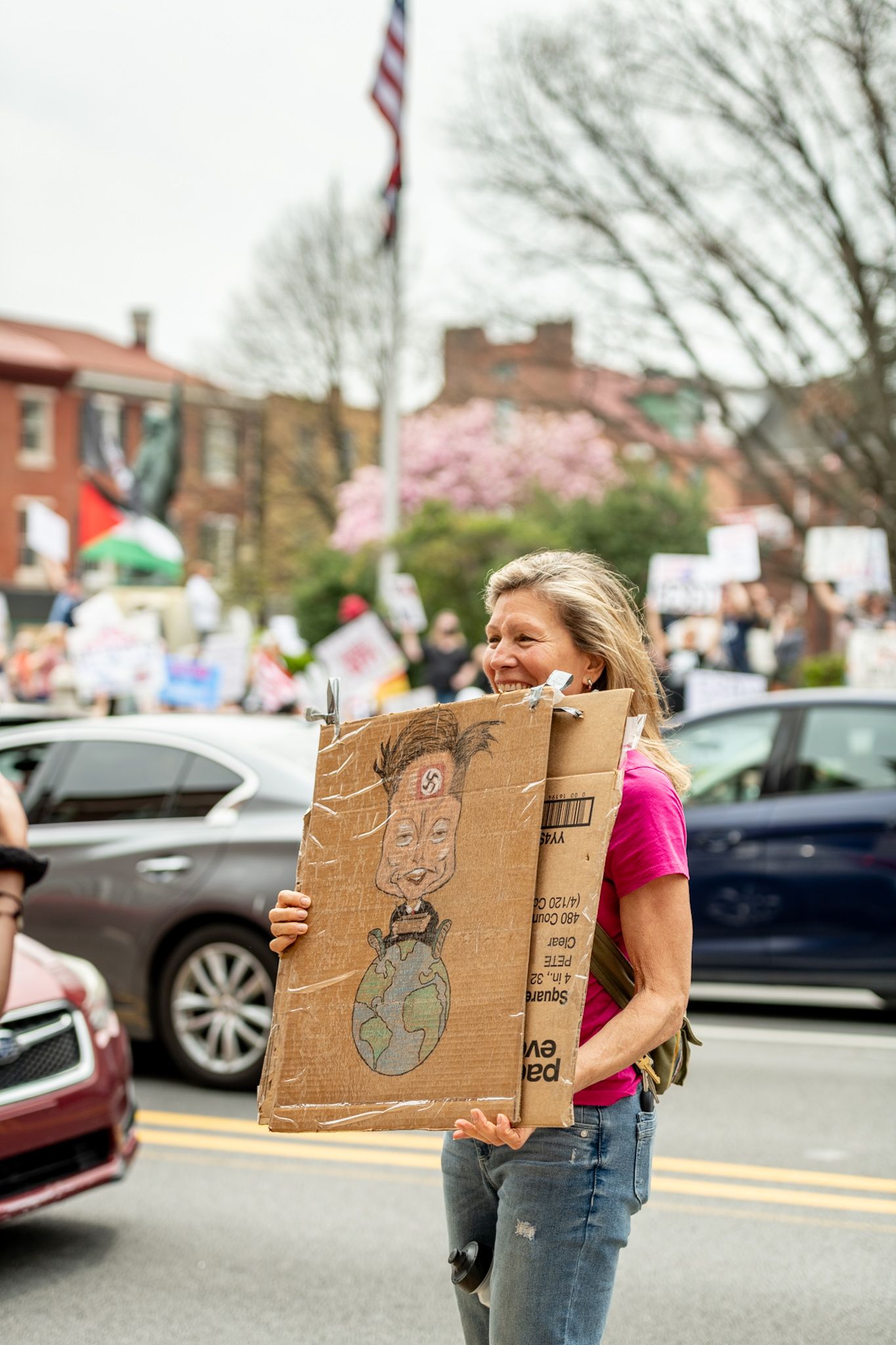 Demonstrators holding cardboard protest signs in an urban street.