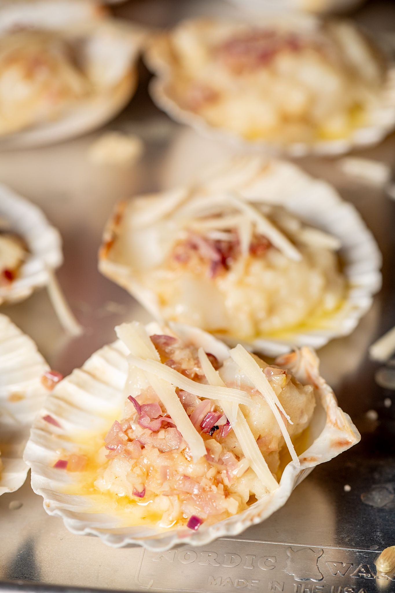 Close-up of seafood appetizers served in white scallop shells with garnishes.