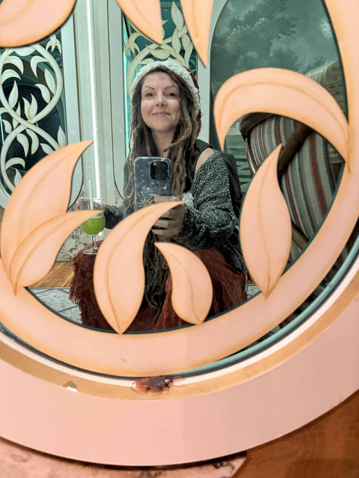A sequence of mirror reflections showing a person peeking through decorative pink and white swirls on a glass surface.