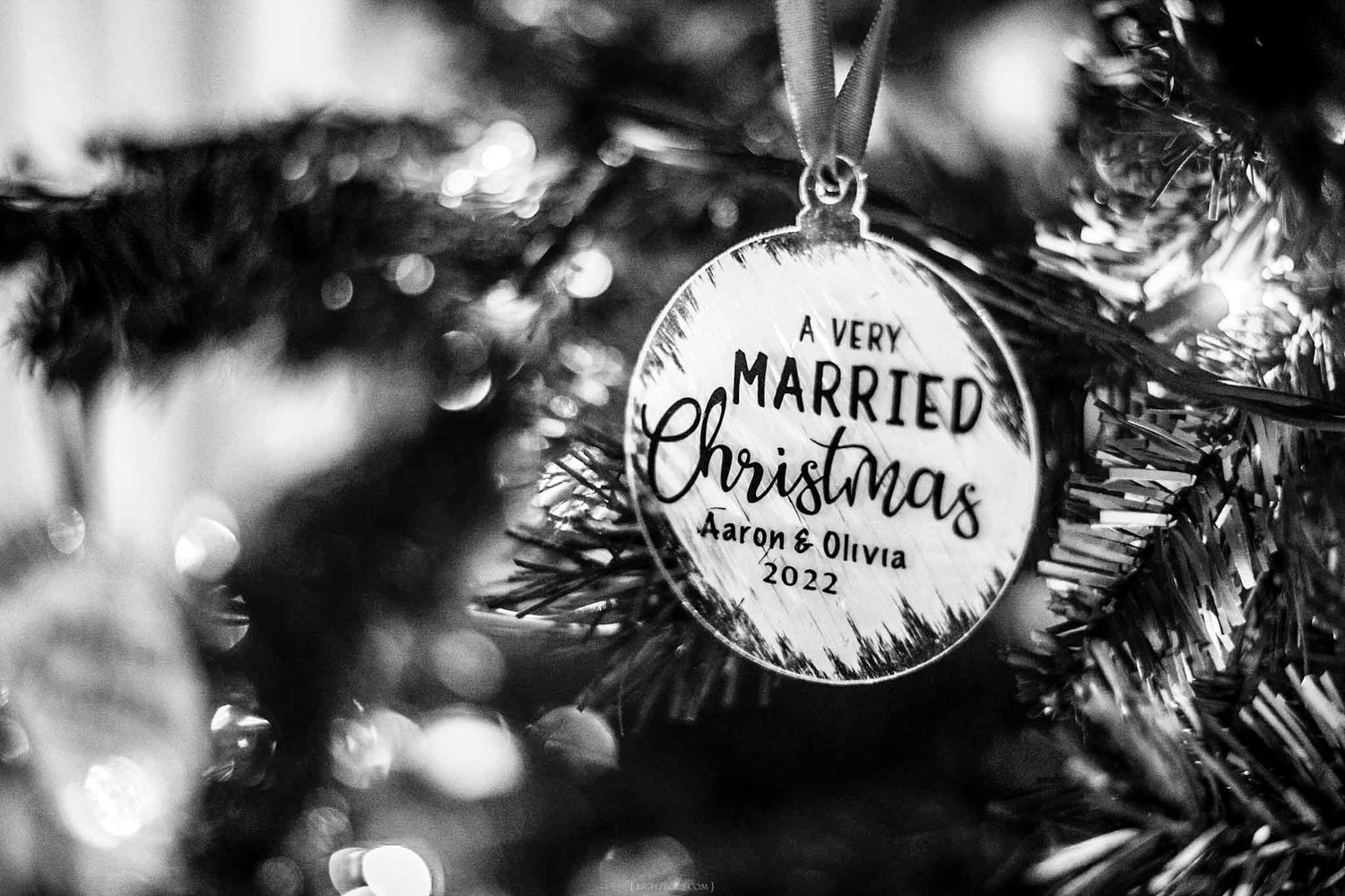 Black and white photo of a married Christmas ornament on a tree reading Aaron and Olivia 2022.