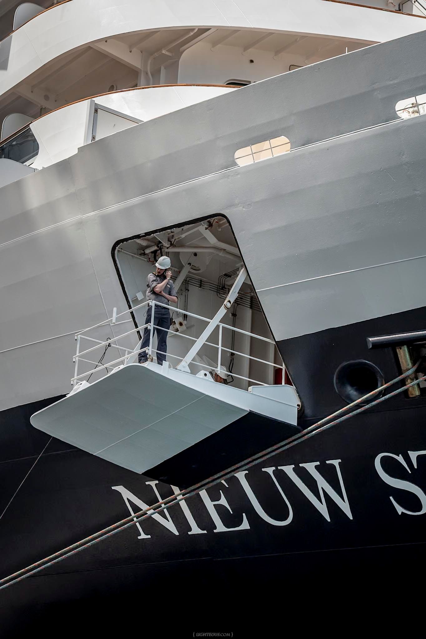 Worker in hard hat stands on deck of cruise ship Nieuw Statendam, viewed from below at a Dutch shipyard.