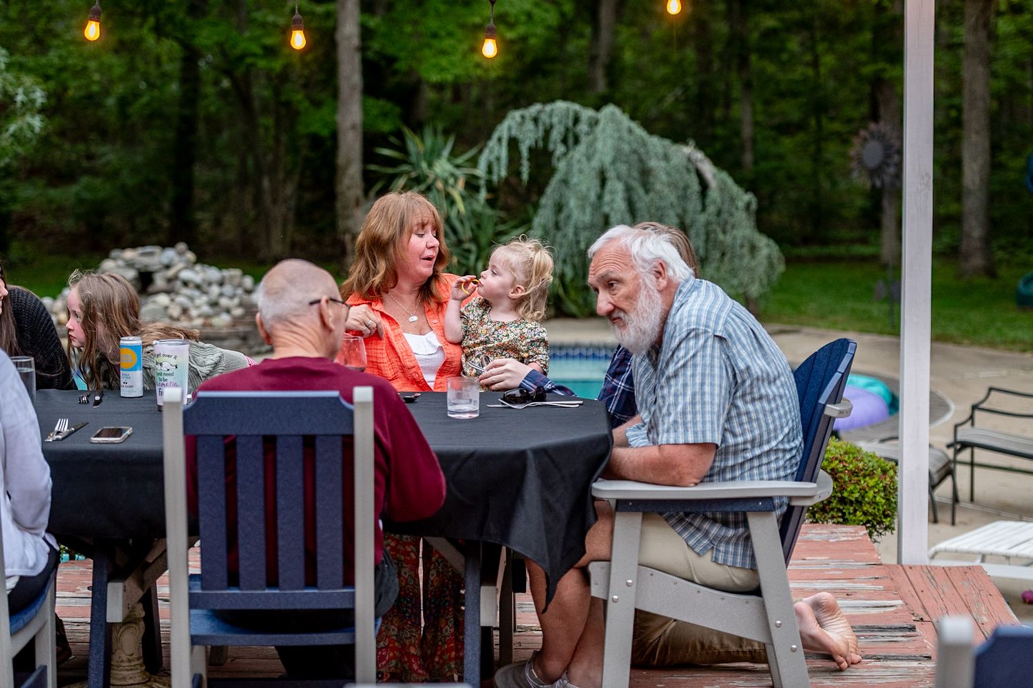 Tables set up outdoors for a social gathering with string lights creating ambient lighting.