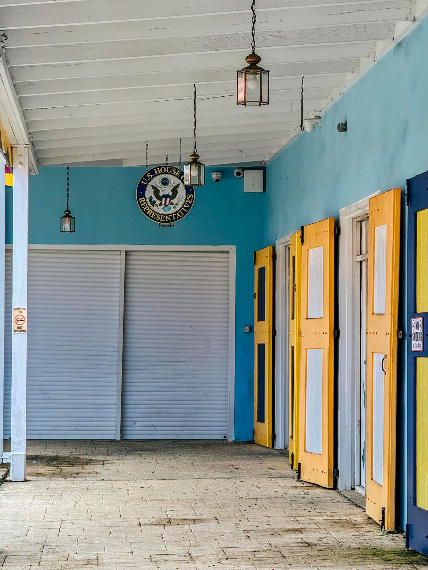 Blue building exterior with yellow doors, hanging lanterns, and U.S. Navy seal on wall.
