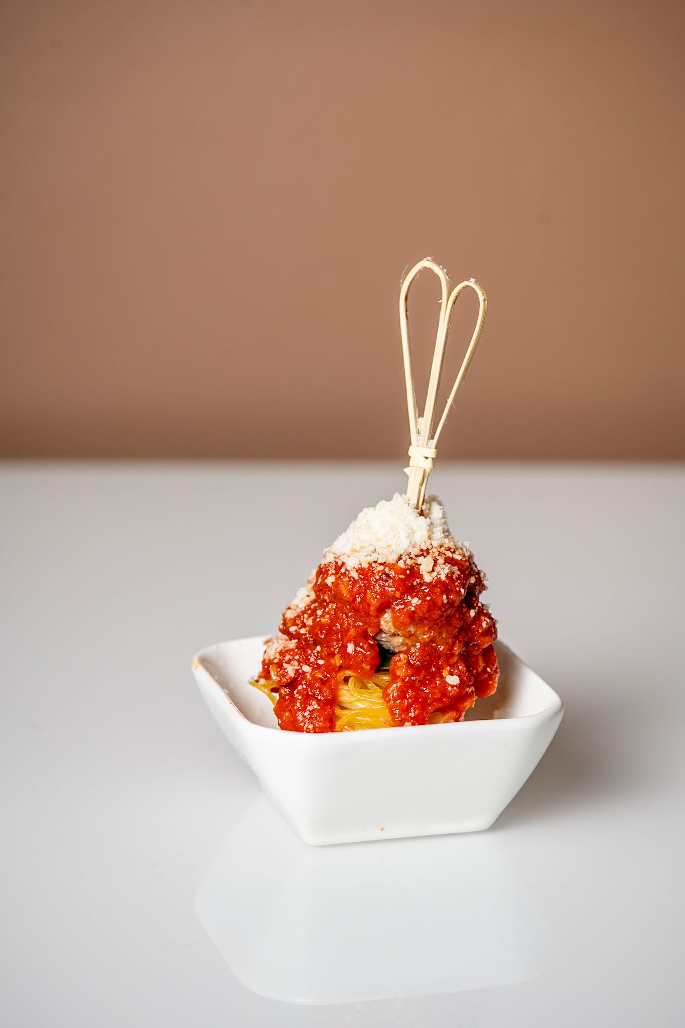 Red caviar appetizer garnished with thin sticks served in a white geometric bowl.