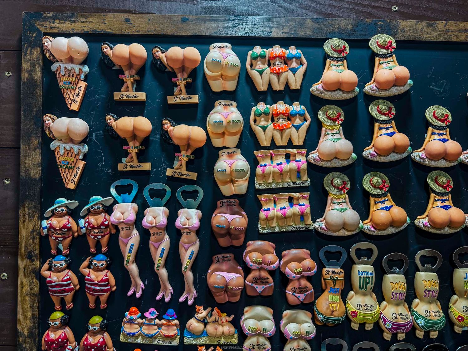 Collection of novelty souvenir bottle openers and magnets with humorous body-themed designs on display.