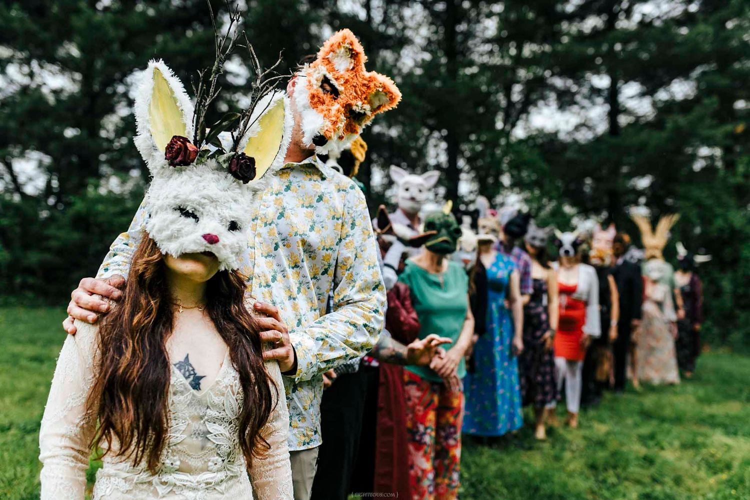 People wearing decorative rabbit masks and colorful costumes stand in a line outdoors at a whimsical festival event.