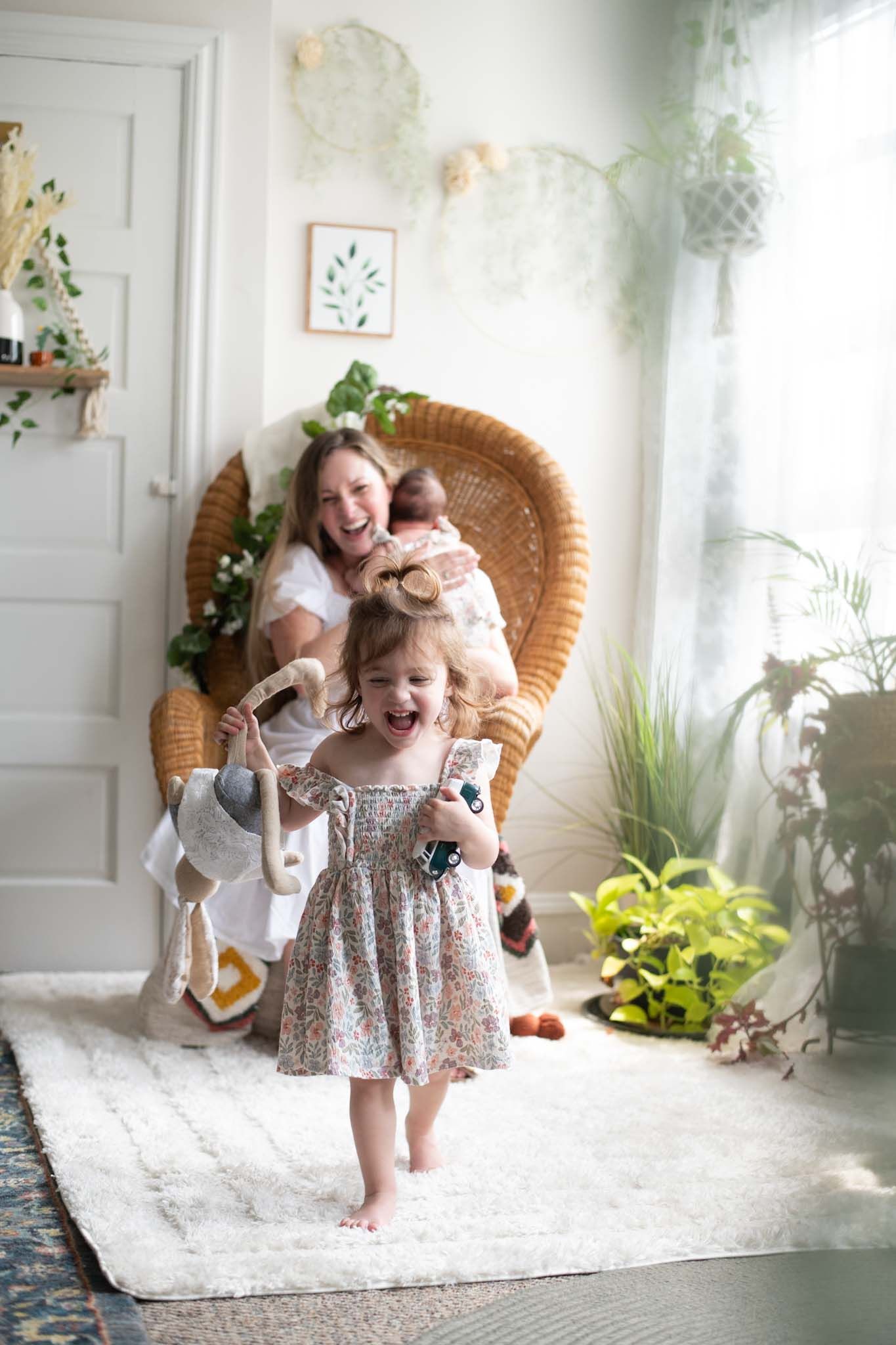 Candid moments of play and laughter captured on a white rug in a bright, plant-filled room.