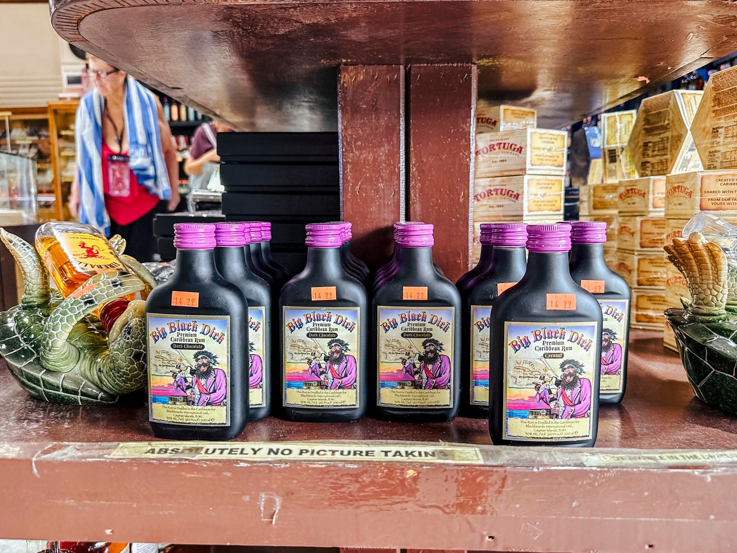 Bottles of Big Boss juice hot sauce displayed on a rustic red wooden shelf in a country store.
