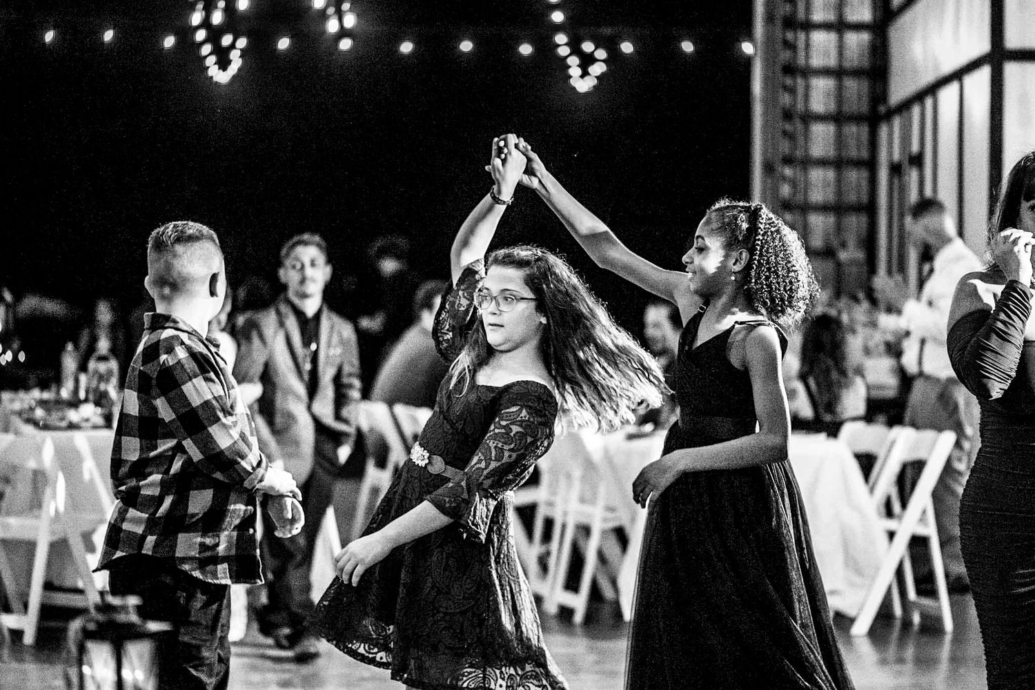 Kids dancing joyfully at a wedding reception in black and white photography.