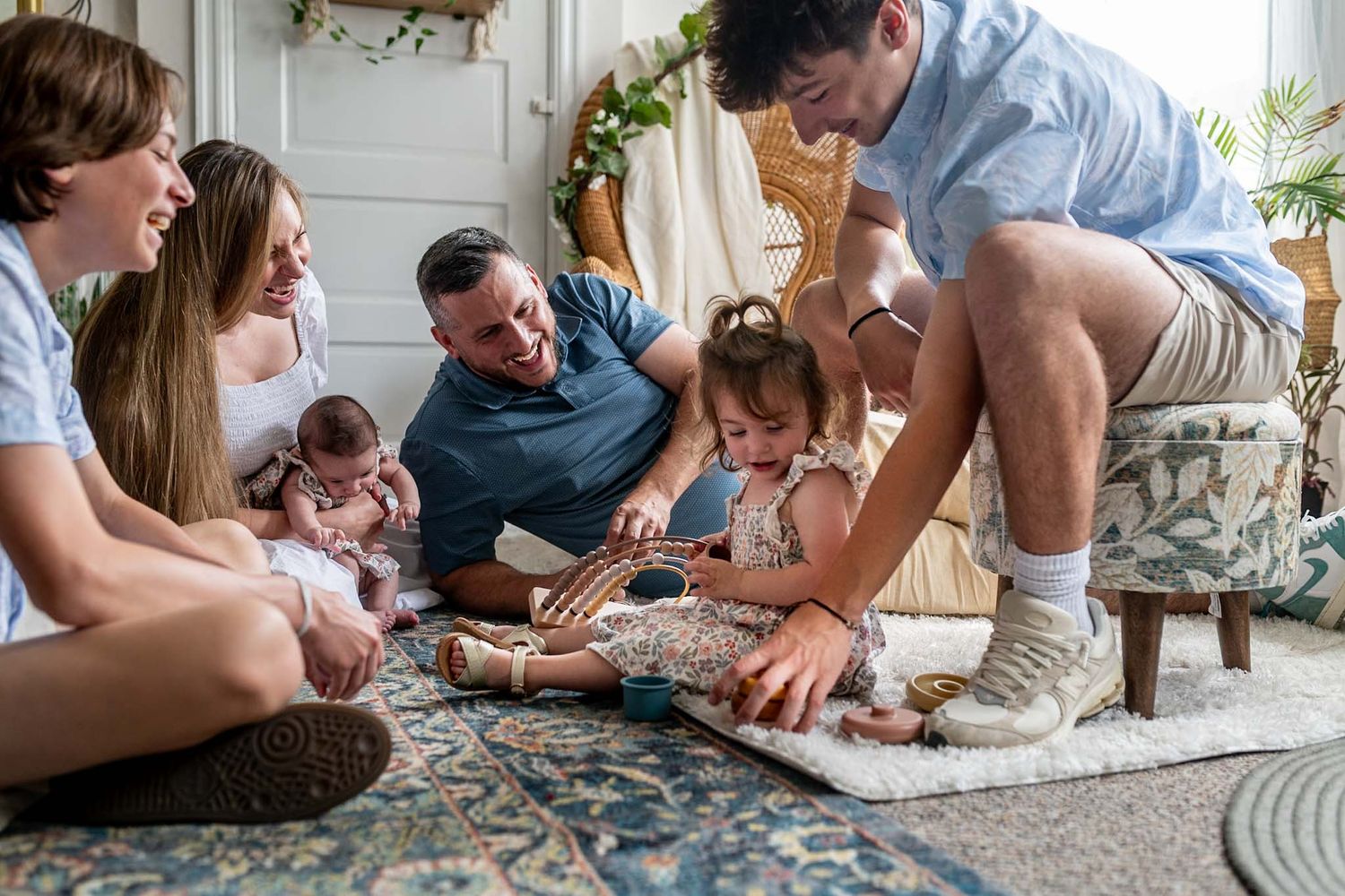Family members gather on a patterned rug for playtime in a bright, modern living space.