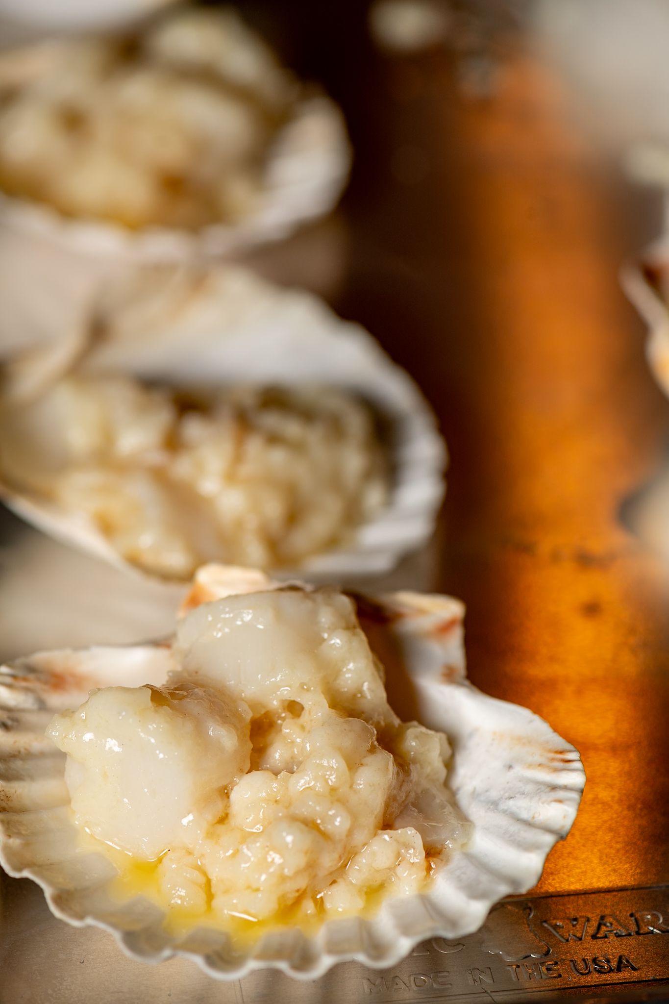 Fresh scallops in shells with butter sauce captured in macro detail.