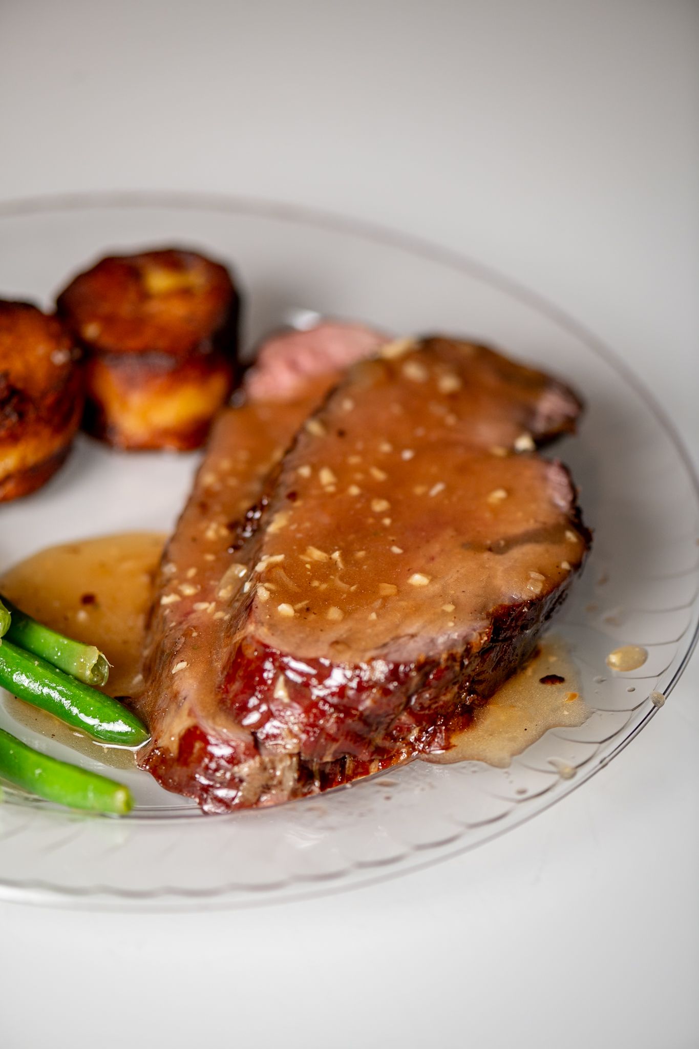 Juicy prime rib steak with sauce and vegetables served on an elegant white plate.