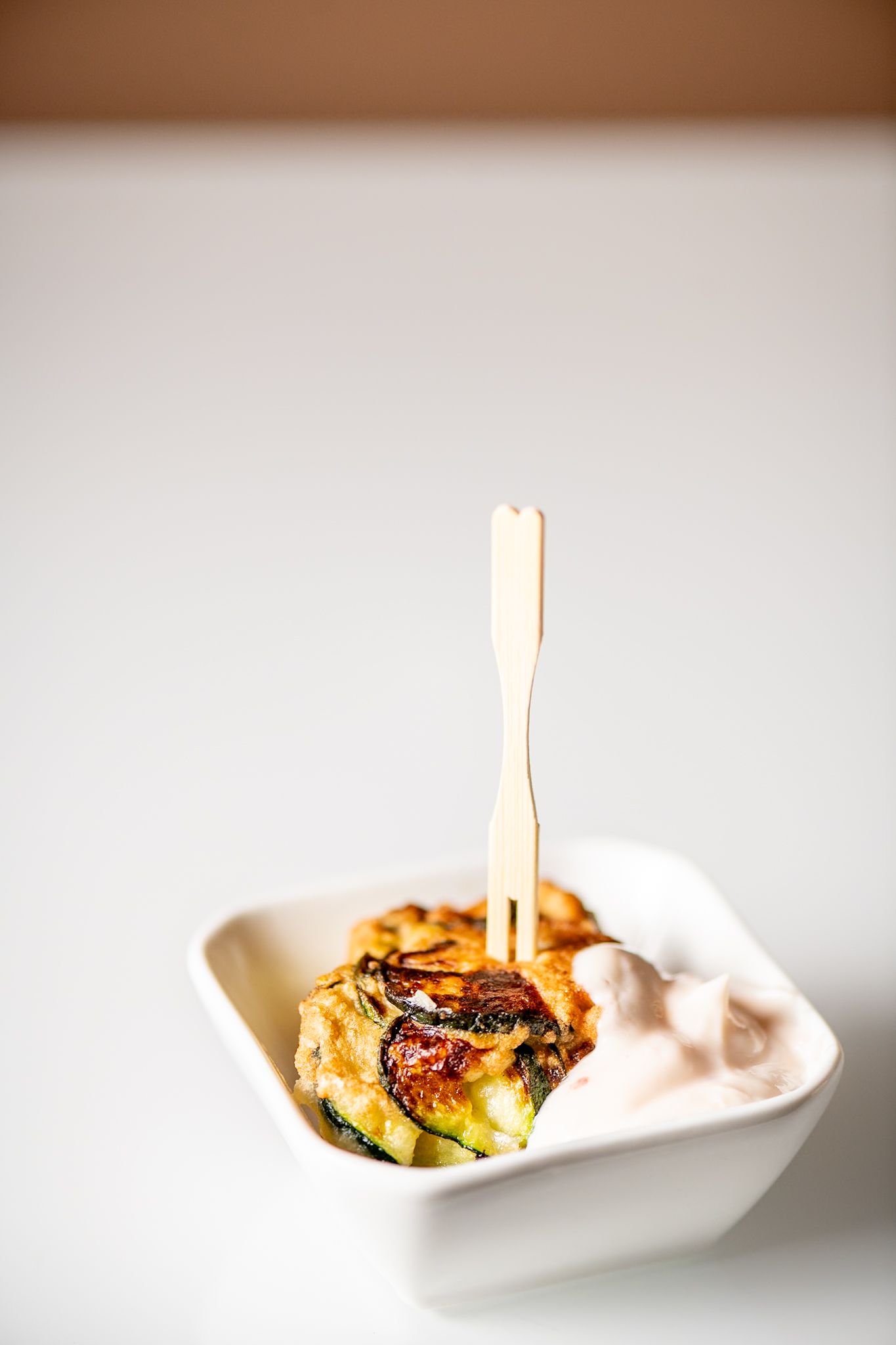 Small appetizer bites served in white ceramic spoons against a light background.