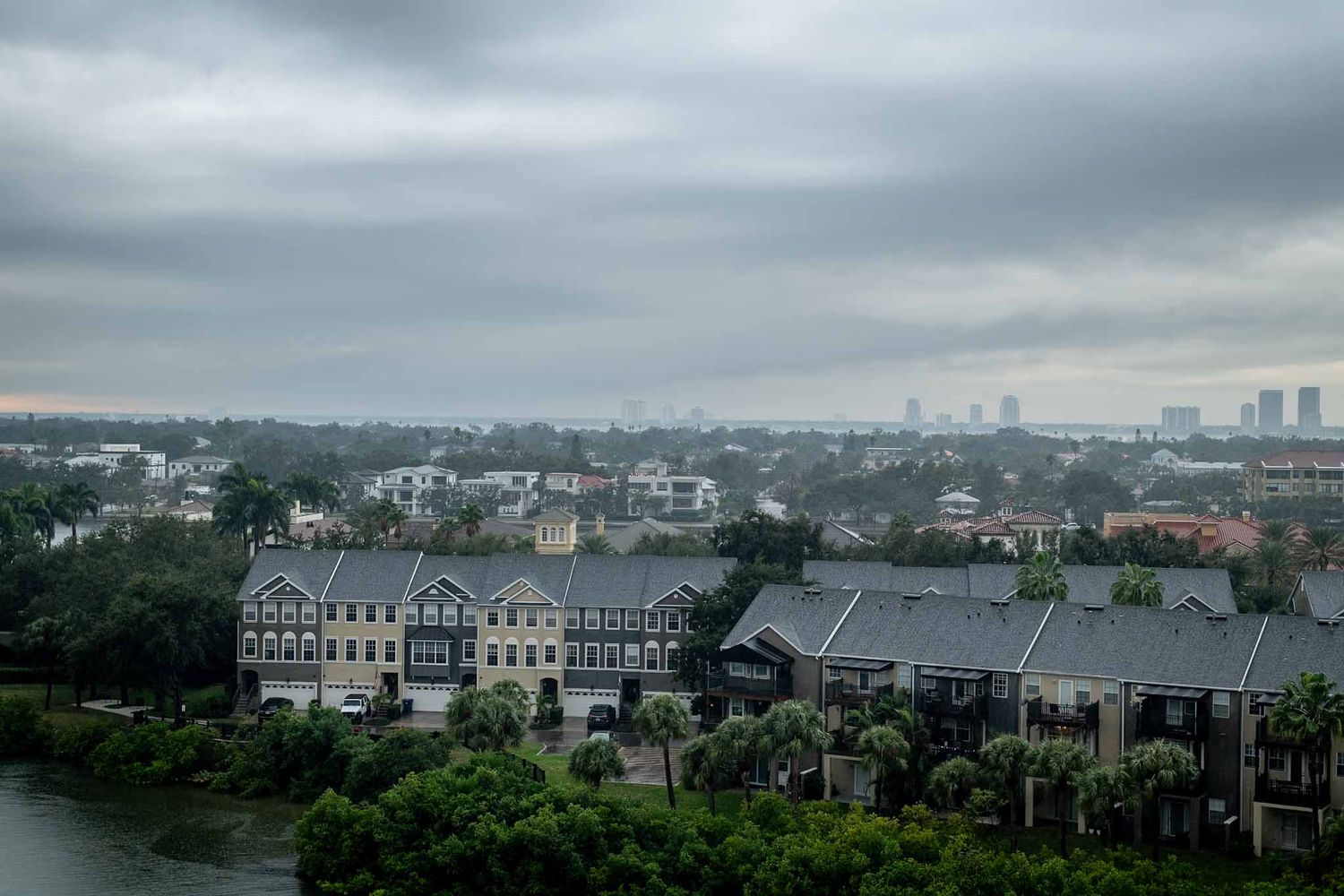 Aerial view of residential buildings and cityscape on a cloudy day with modern towers visible in the distance.