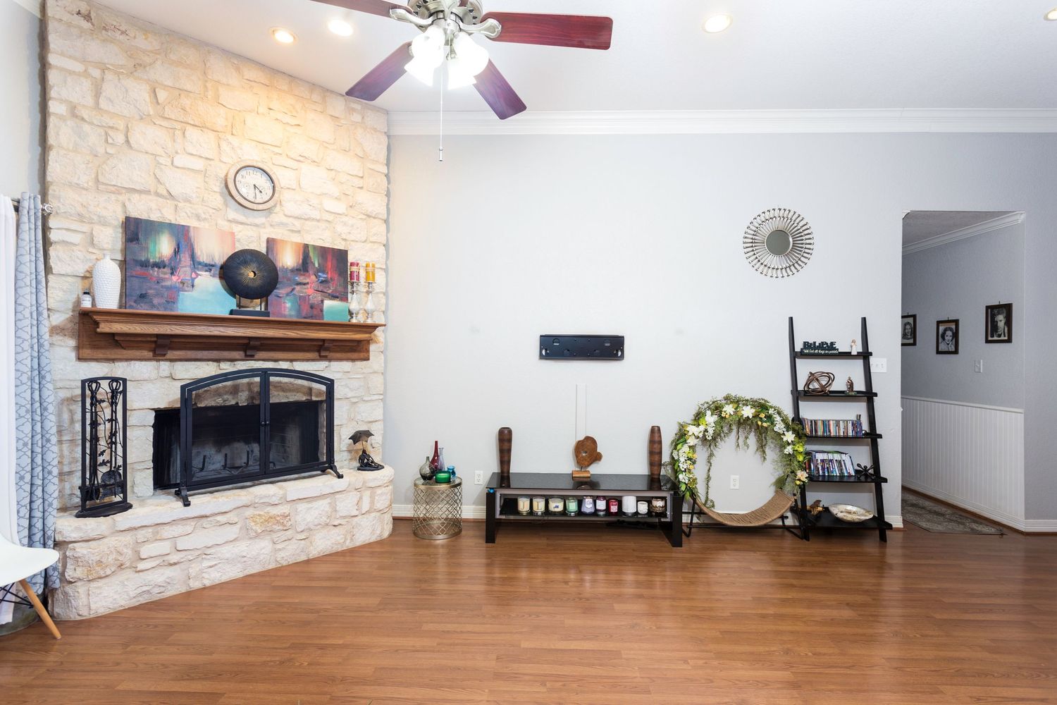 Spacious living room featuring a stone fireplace, hardwood floors, and vaulted ceiling with fan.