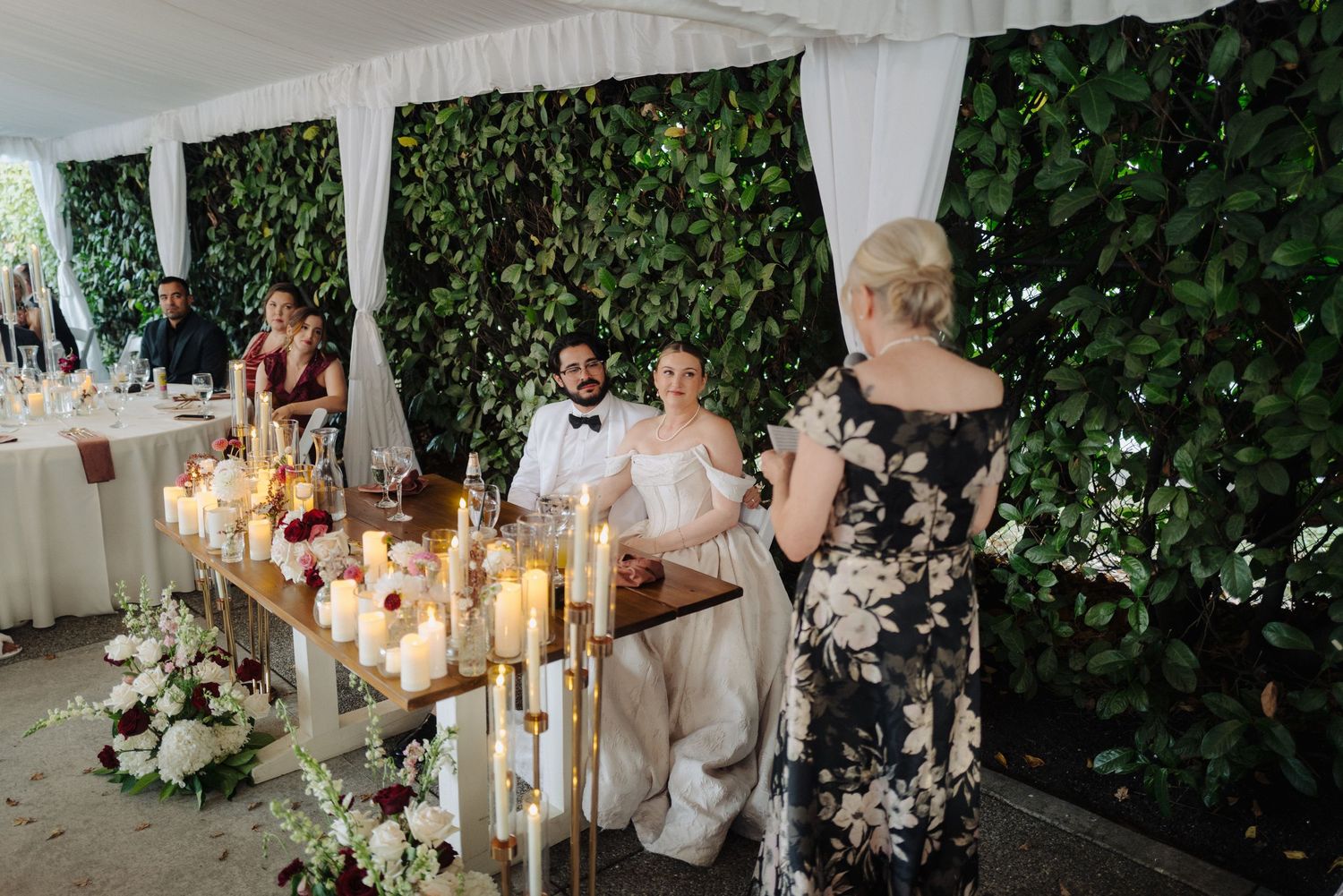 Wedding reception decor featuring greenery and glowing candles in elegant outdoor setting.