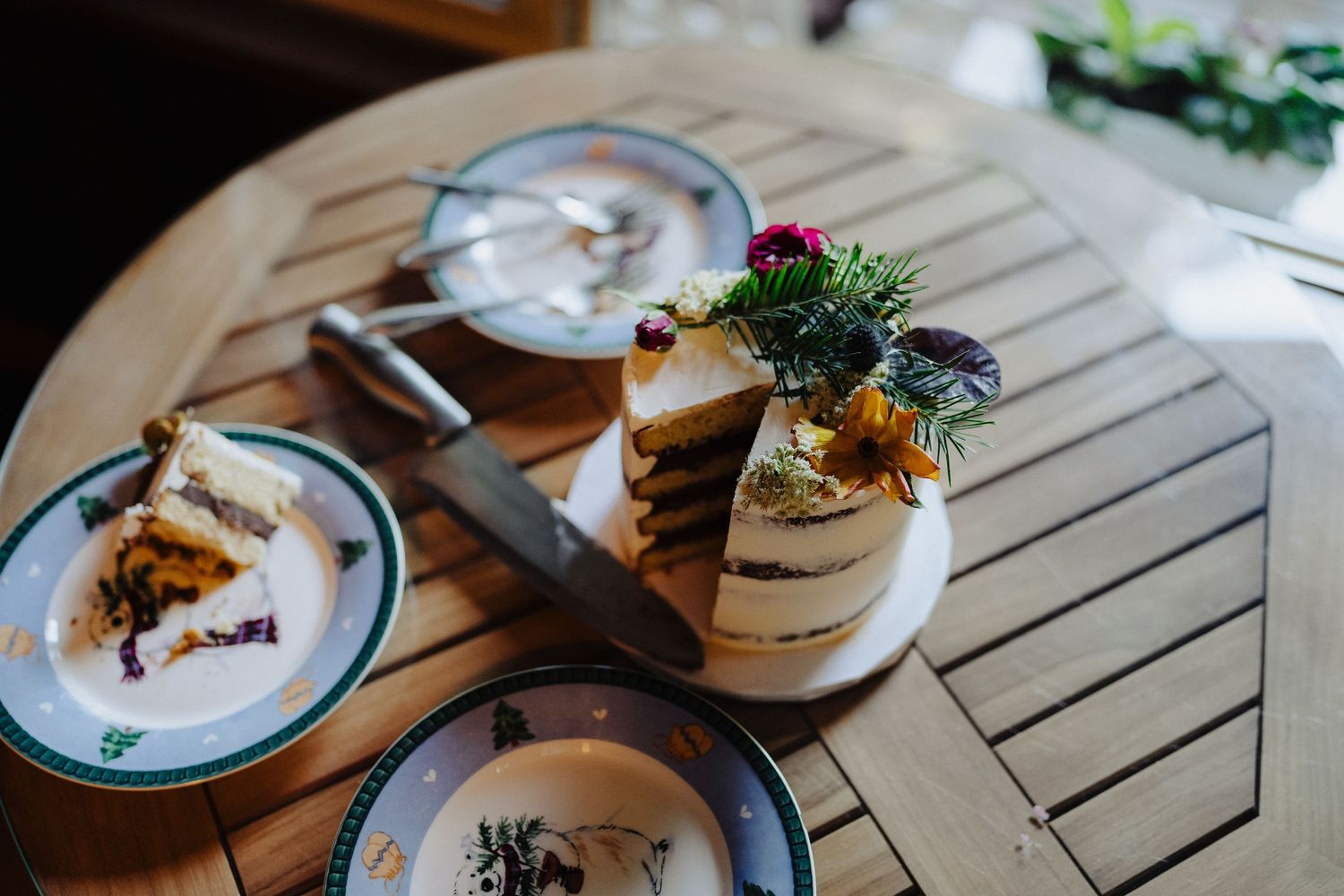 Elegant wedding cake with fresh berries and greenery displayed on wooden table.