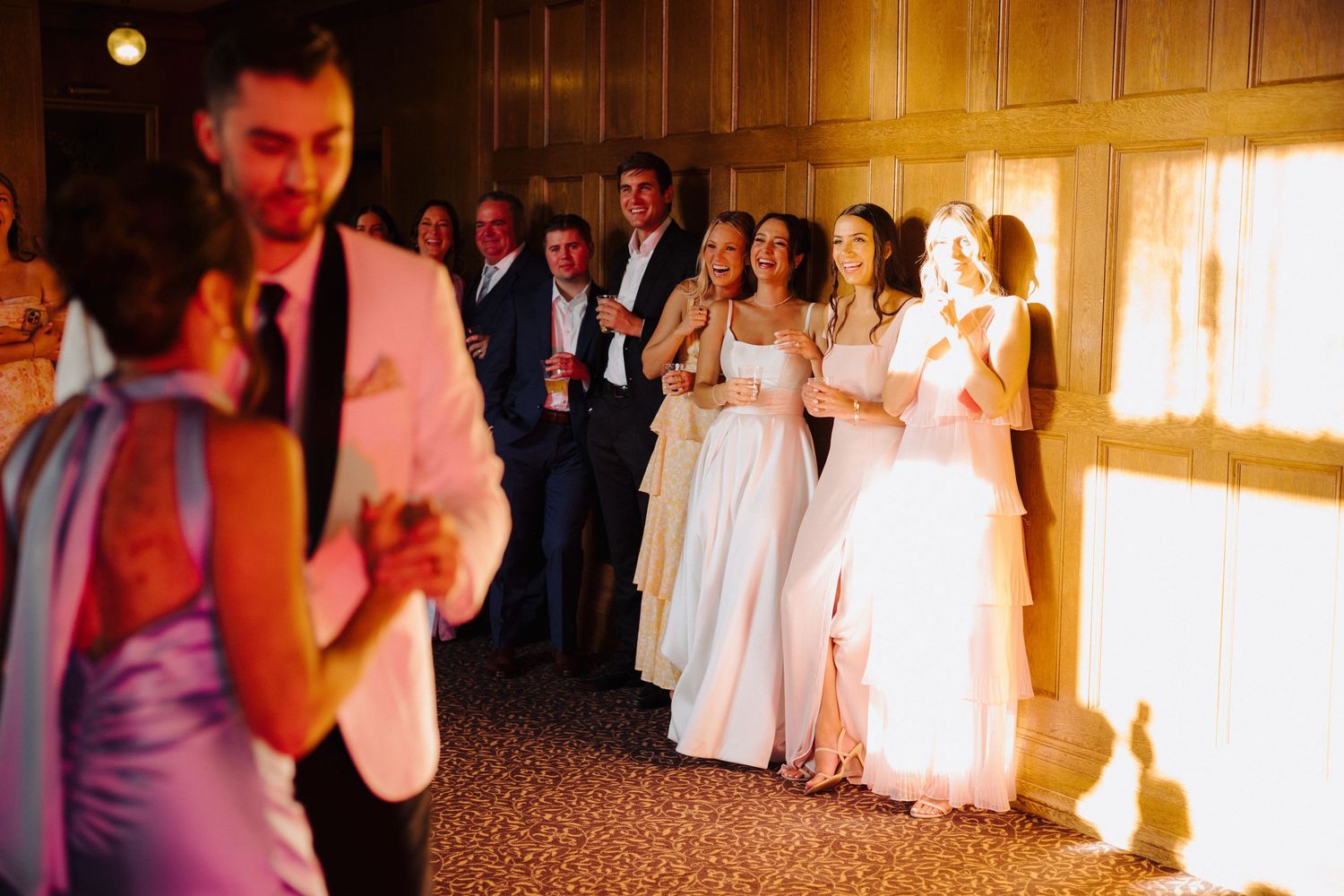Wedding reception scene with warm lighting and guests watching from the sidelines.