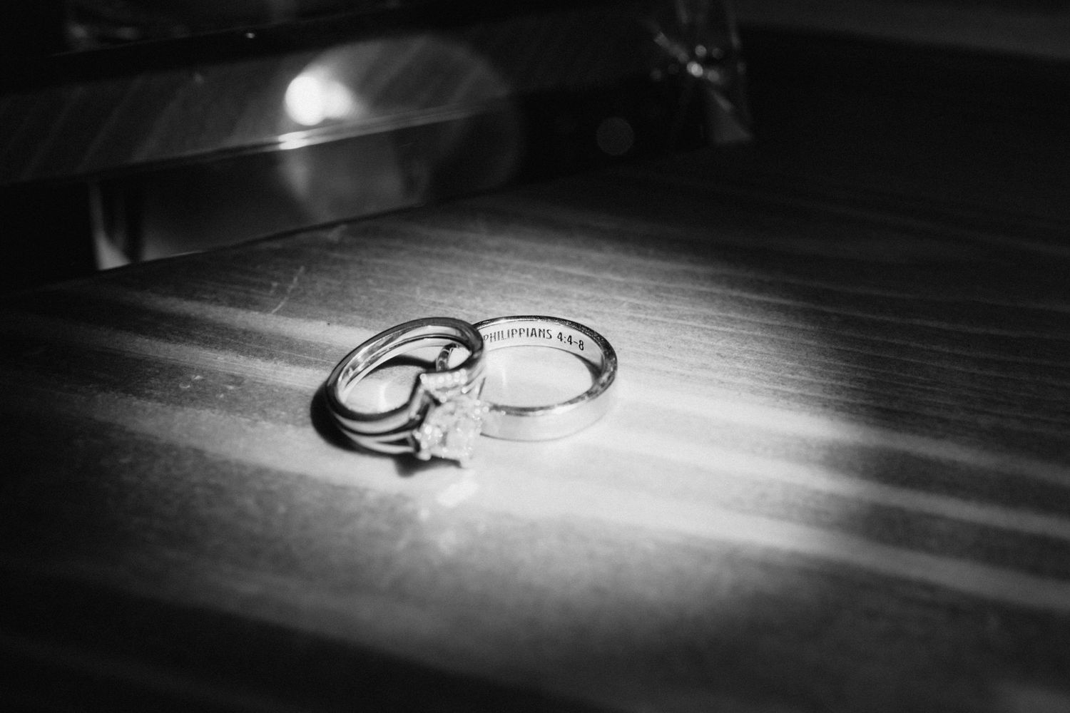 Artistic black and white detail shot of wedding rings with dramatic lighting.