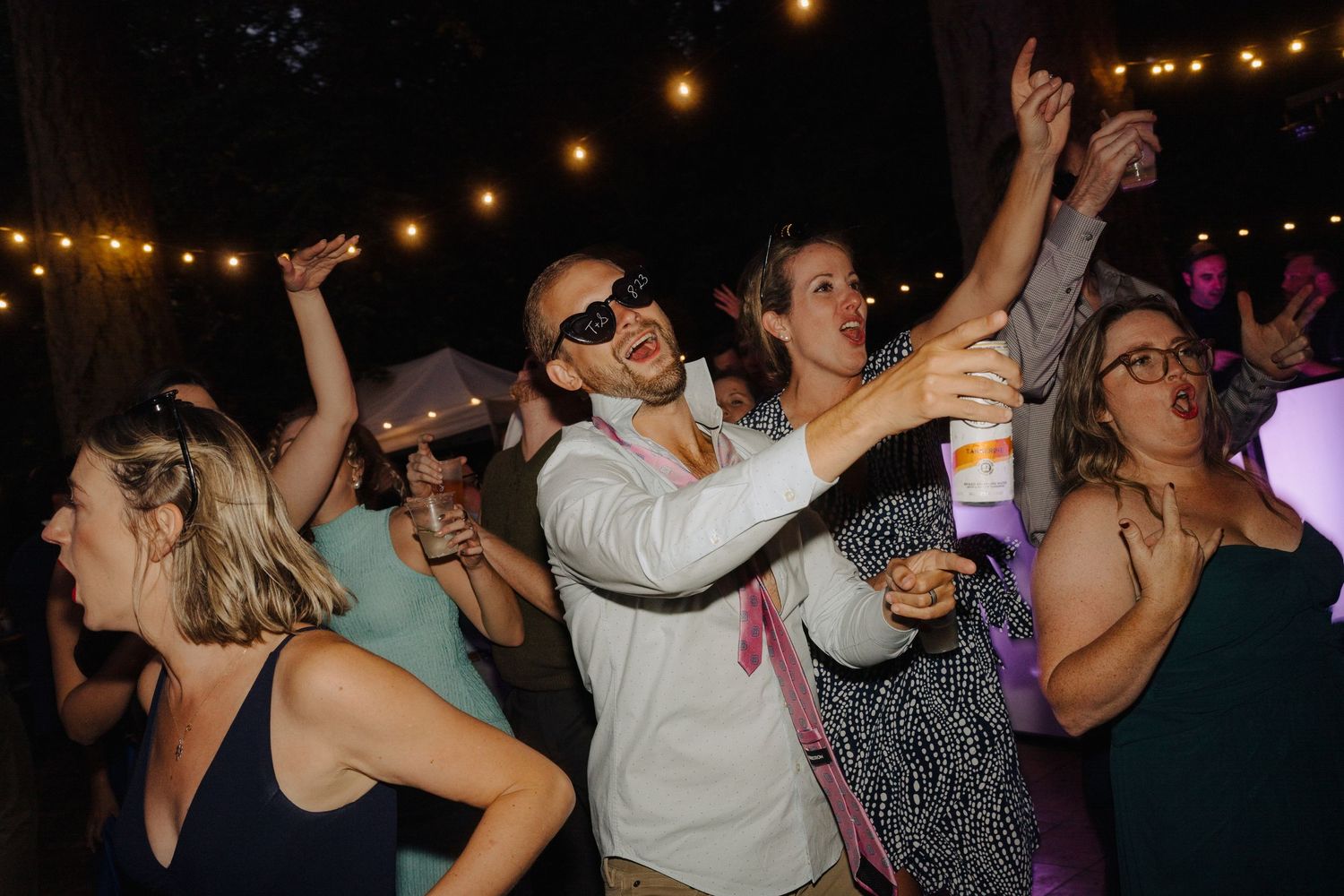 Wedding reception dance party with string lights overhead creating a festive nighttime celebration.