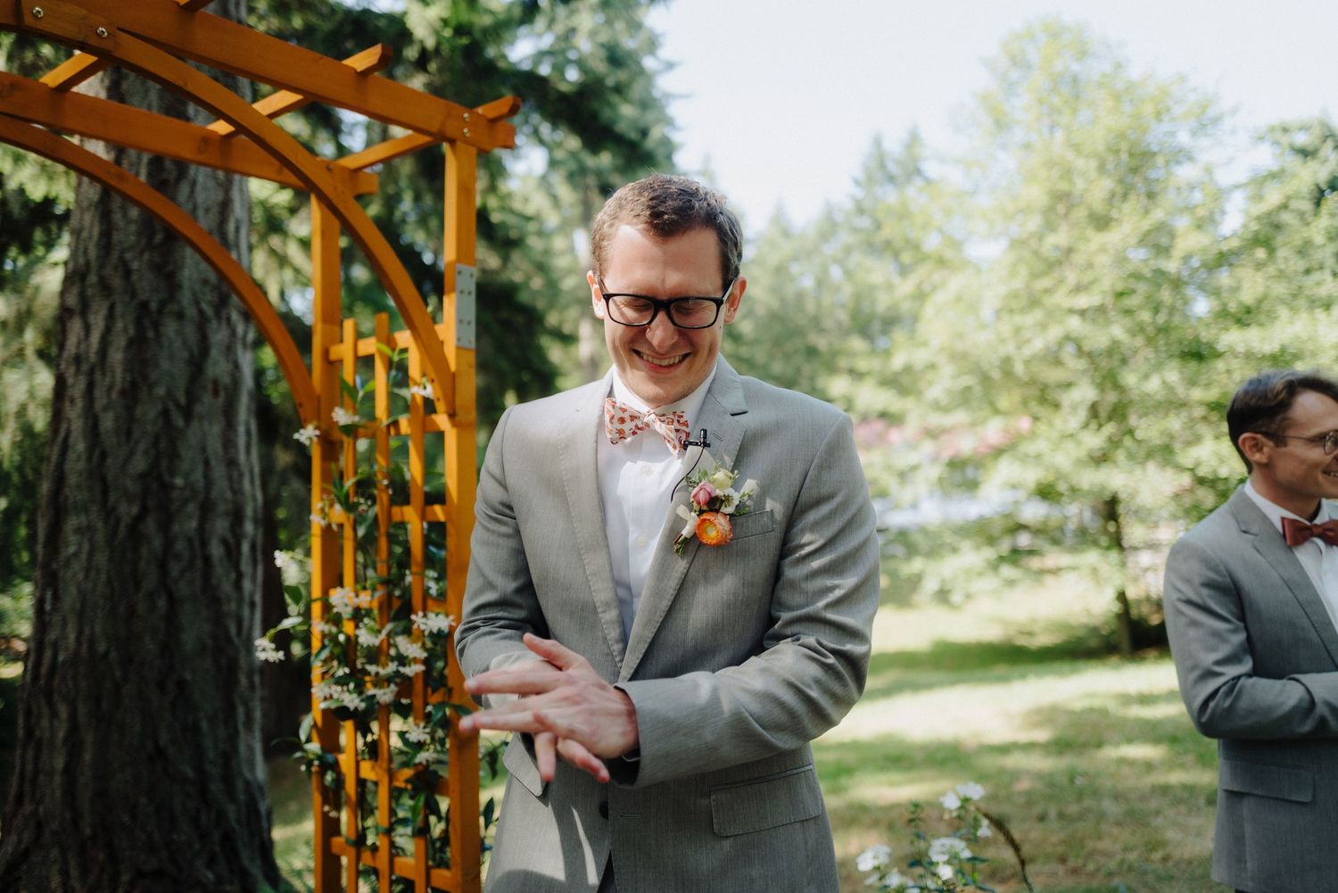 Emotional wedding ceremony moment captured under wooden arch in sunlit forest setting.