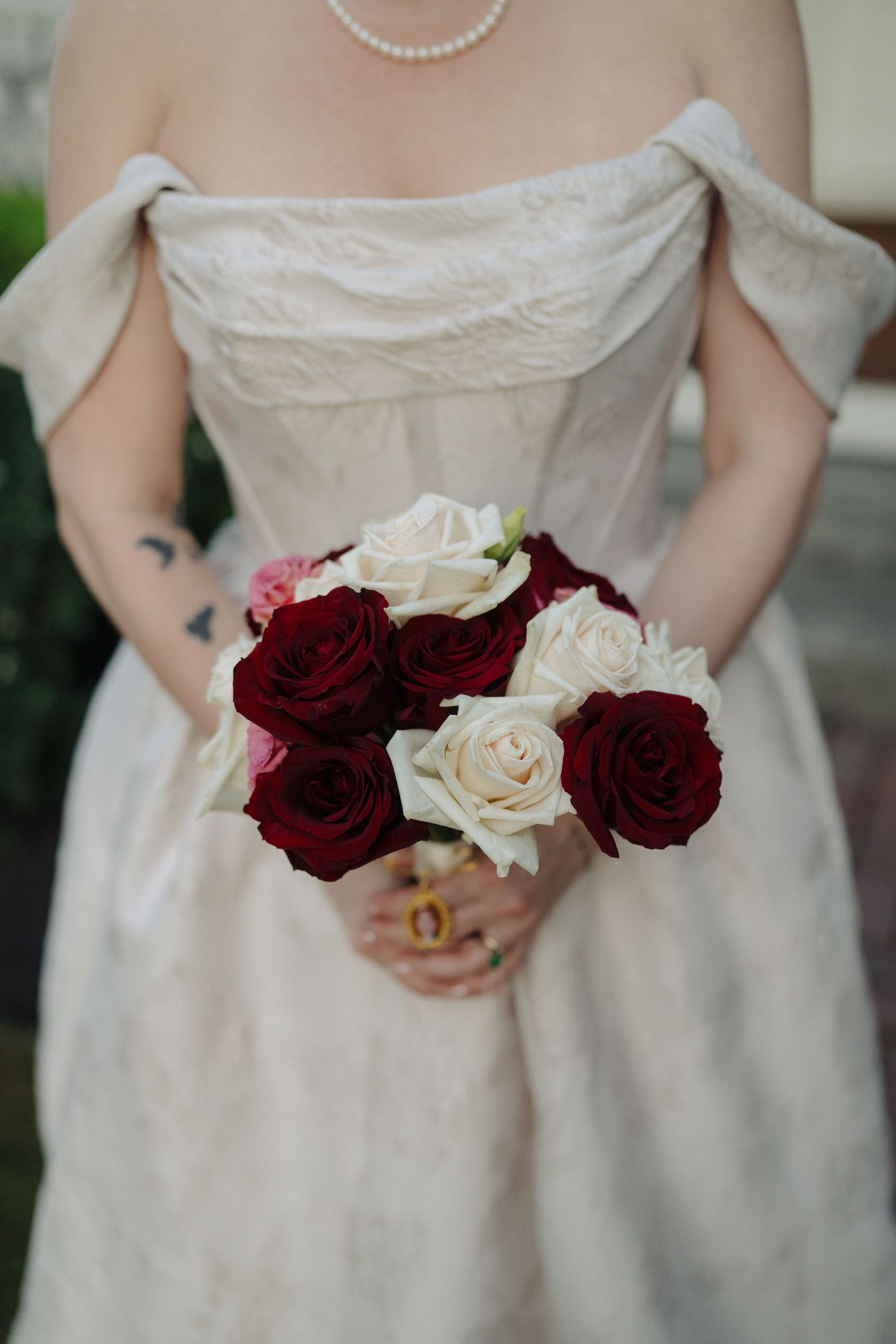 Close-up of red and white roses held against an elegant white wedding dress.