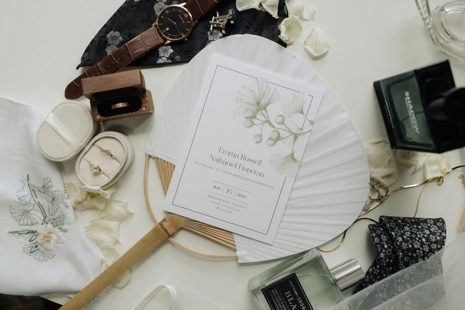 Wedding stationery and invitations arranged with beauty products and decorative elements on white surface.