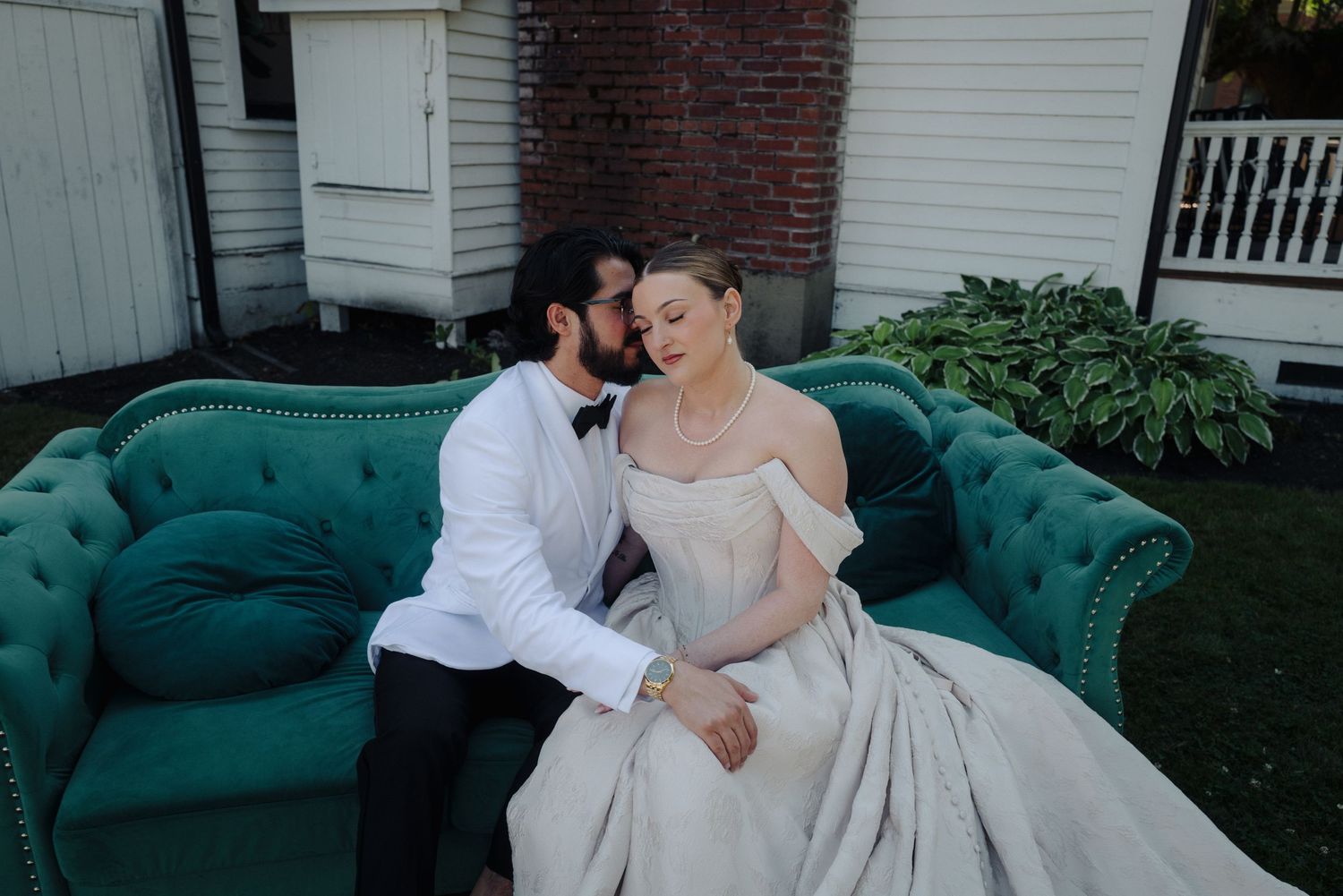 Intimate moment shared on an emerald green vintage sofa outdoors.