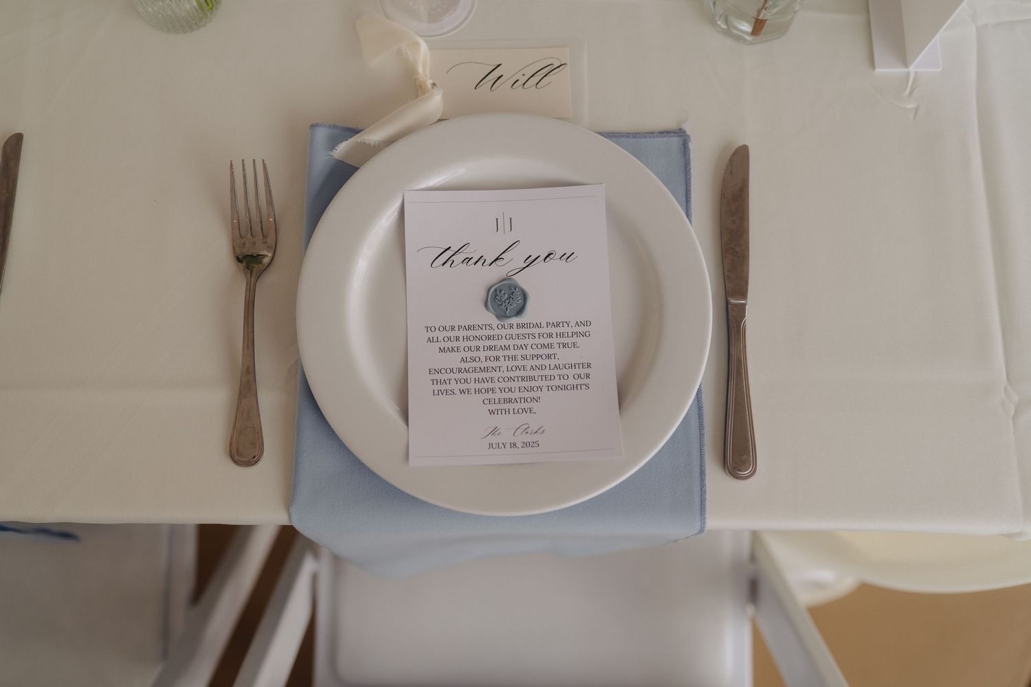 Elegant wedding reception table setting with white plates and calligraphy place cards.