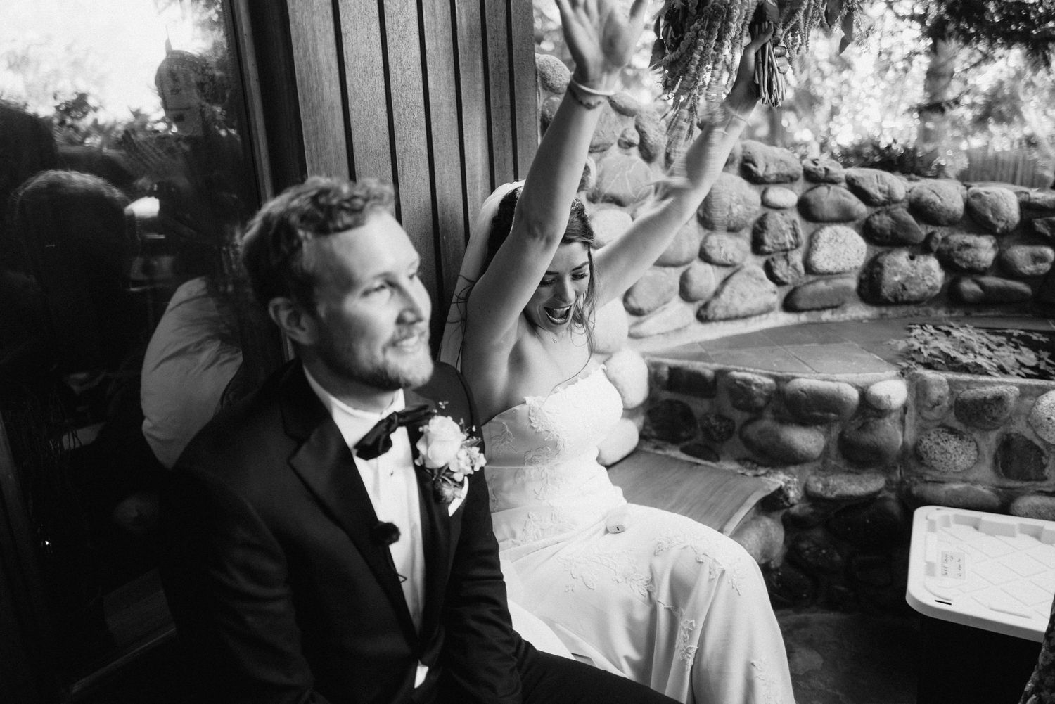 Black and white photo captures intimate wedding moments in a rustic stone venue setting.