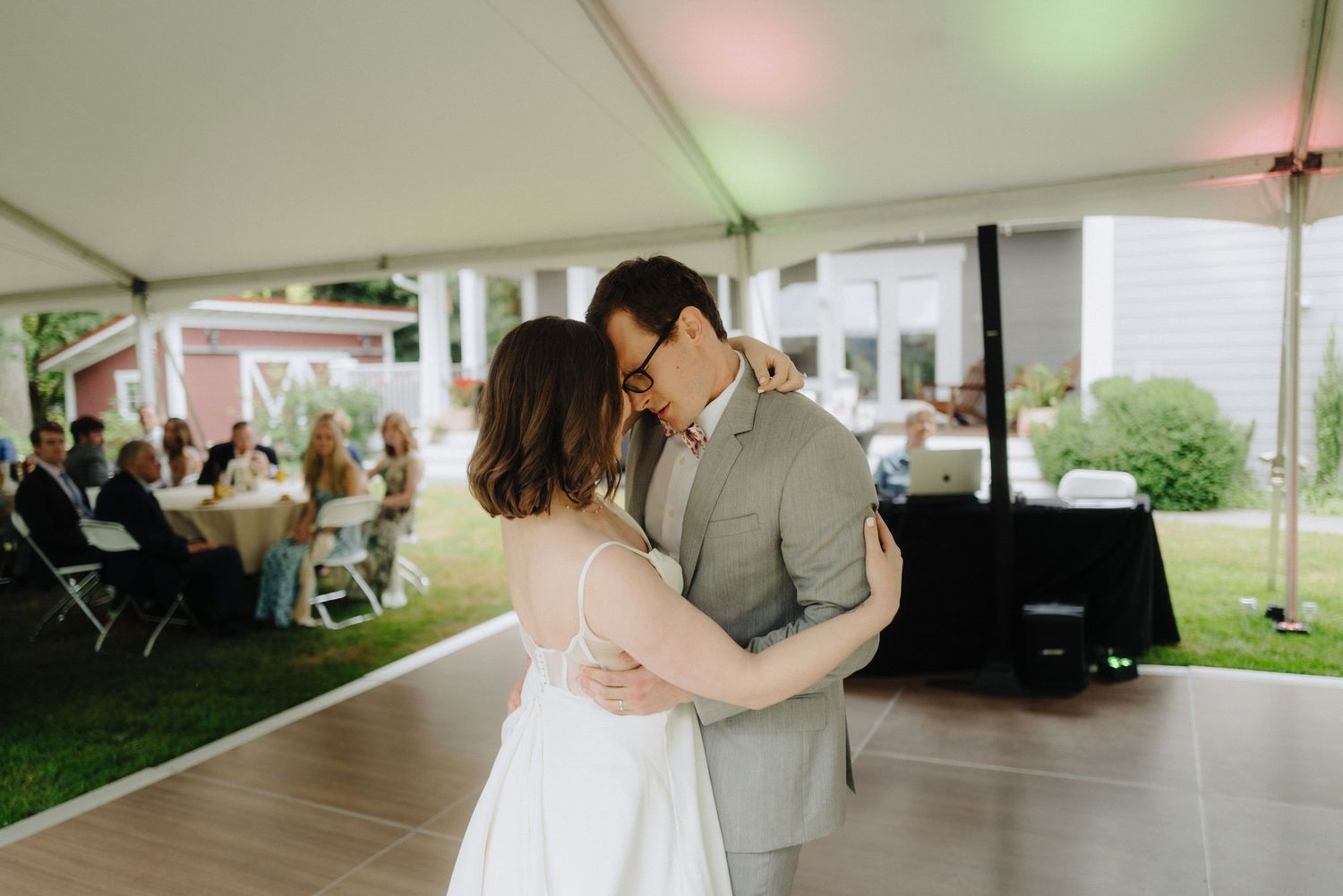 Wedding reception tent with colored lighting and couples dancing on the floor.