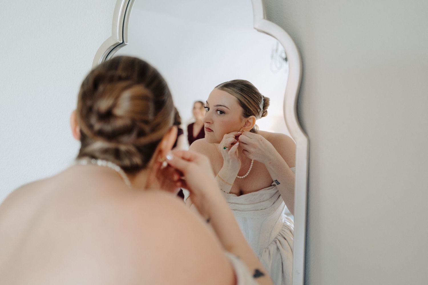 Mirror reflections show a bride getting ready with hair and makeup styling before her wedding ceremony.