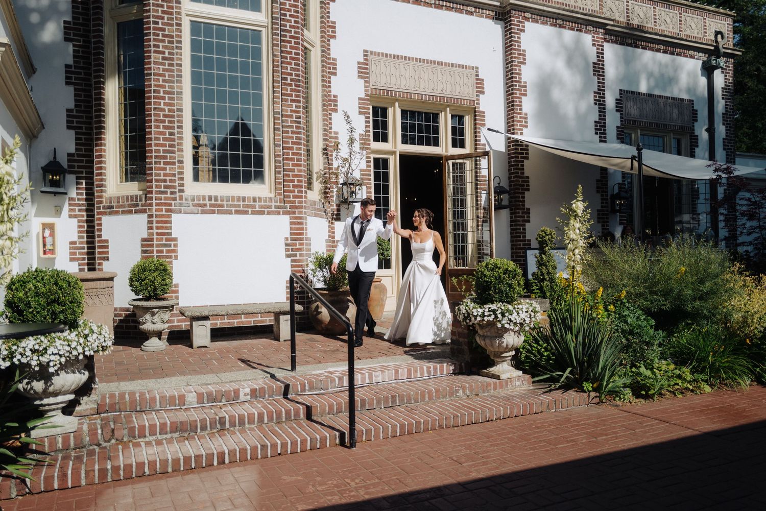 Panoramic view of a brick colonial style building with wedding decorations and guests.