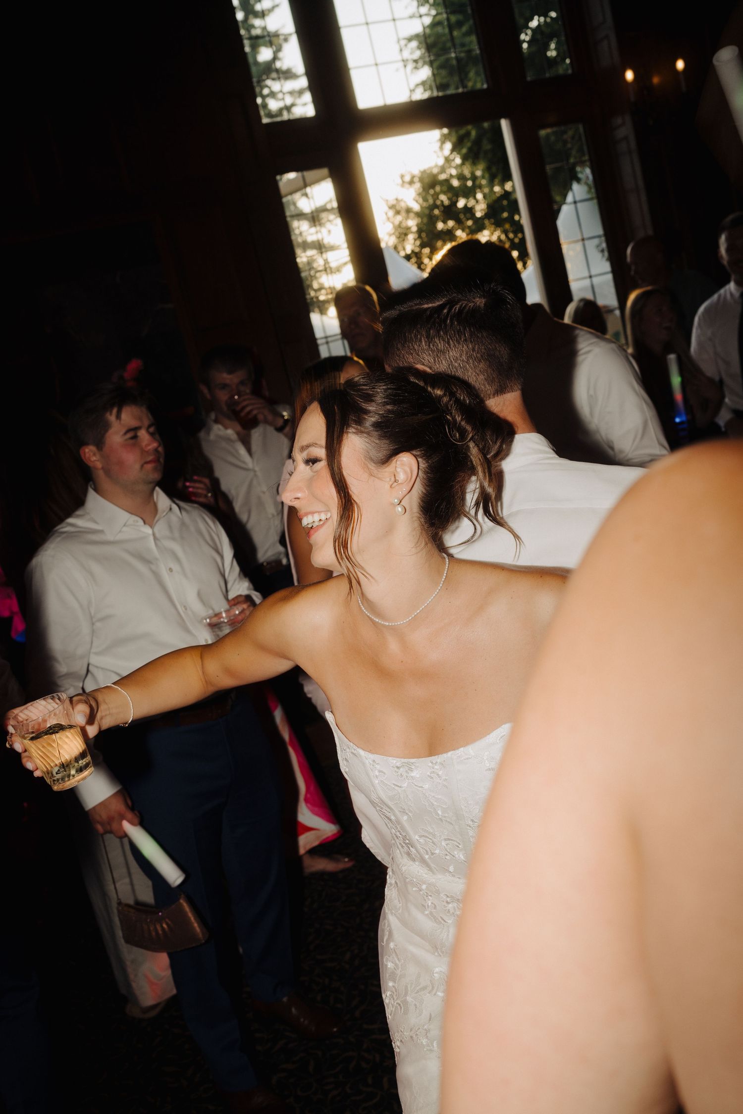Wedding reception guests dancing and celebrating in a dark indoor venue.