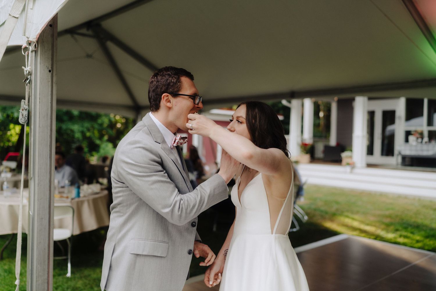 Wedding couple shares first dance under white tent at forest reception.