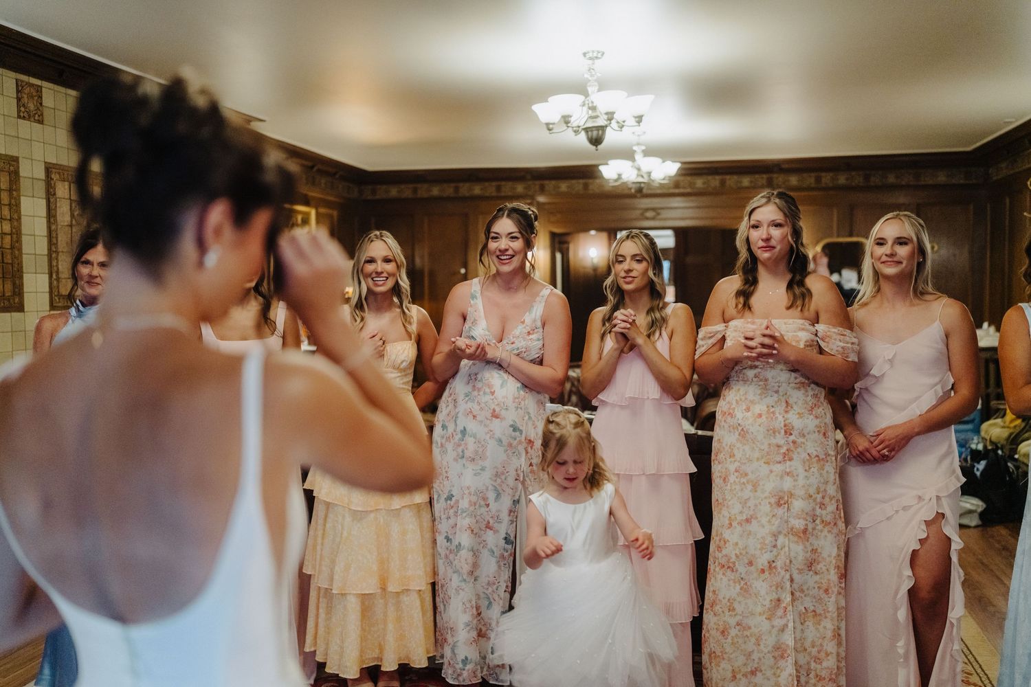 Bridesmaids in pastel floral dresses share joyful moments during a wedding celebration.