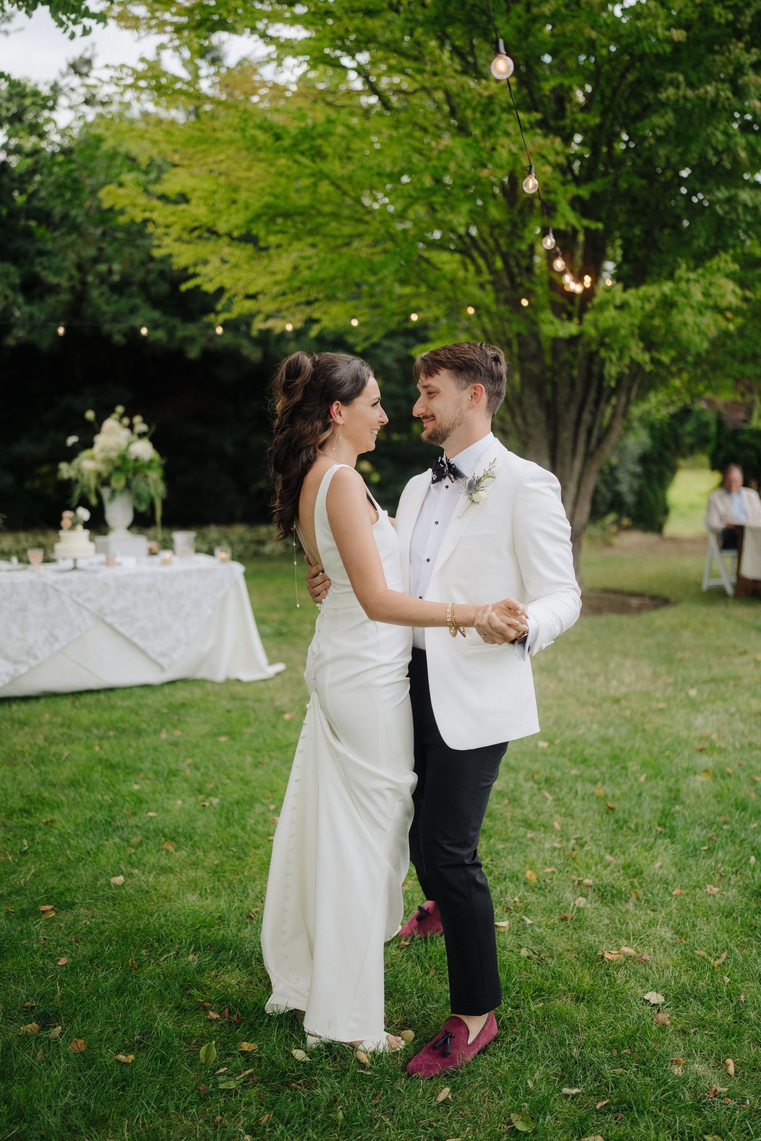 Newlyweds dancing together on grass during their outdoor wedding reception.