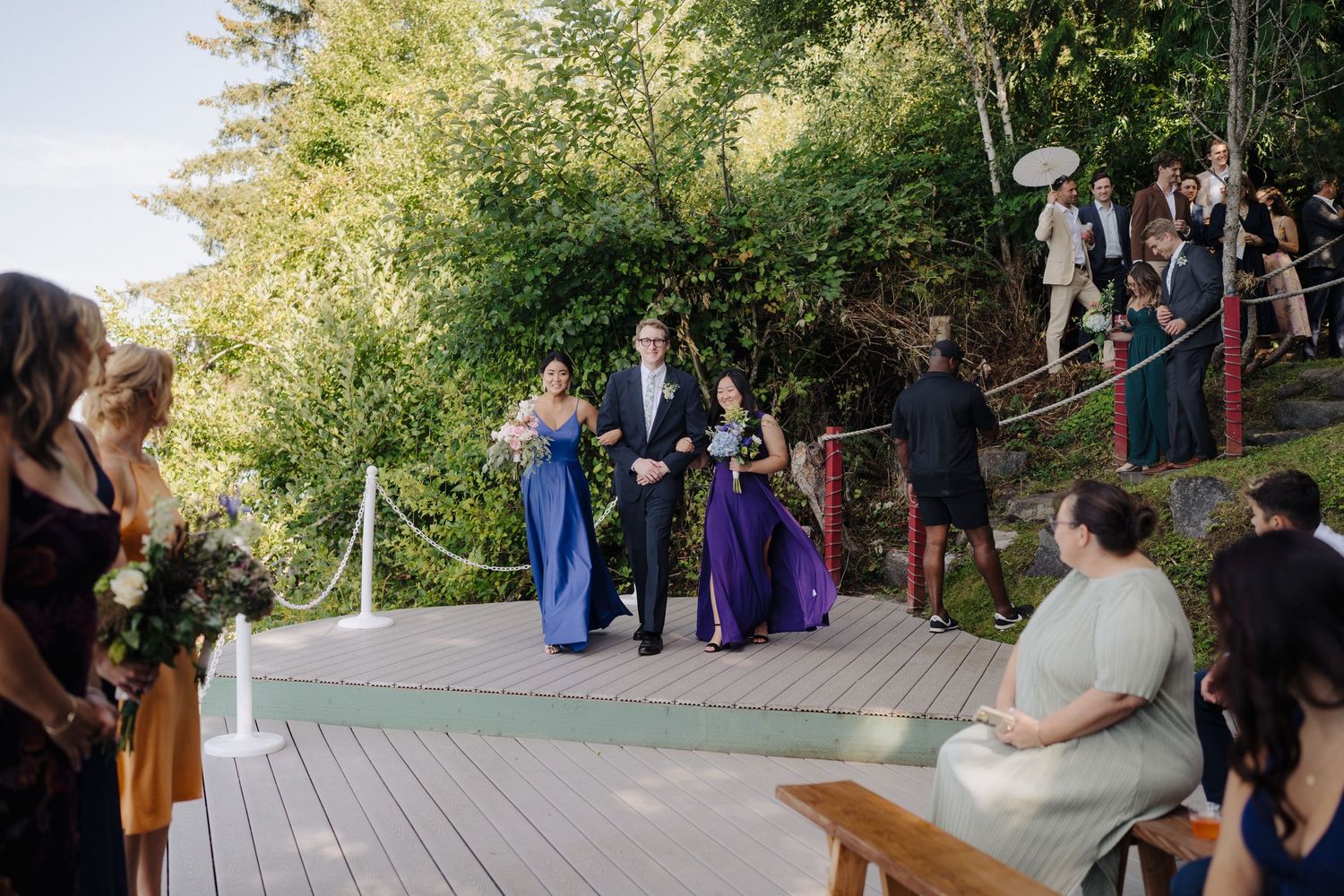 Wedding ceremony takes place on a rustic wooden deck with trees and natural scenery in the background.