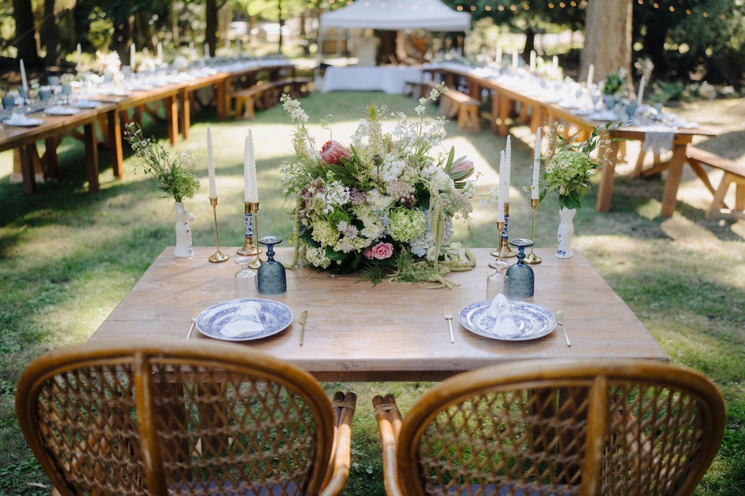 Elegant outdoor wedding reception tables set under string lights with rustic wooden chairs.