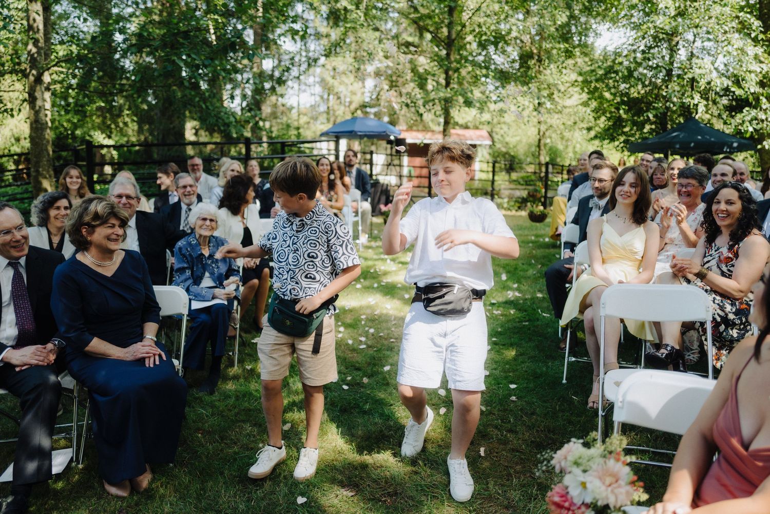 Casual outdoor wedding reception with guests mingling between rows of white chairs.