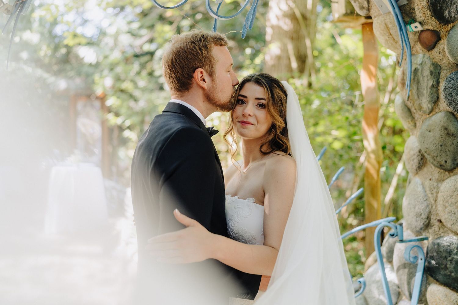 Romantic wedding portrait captured in dreamy natural light with greenery in the background.