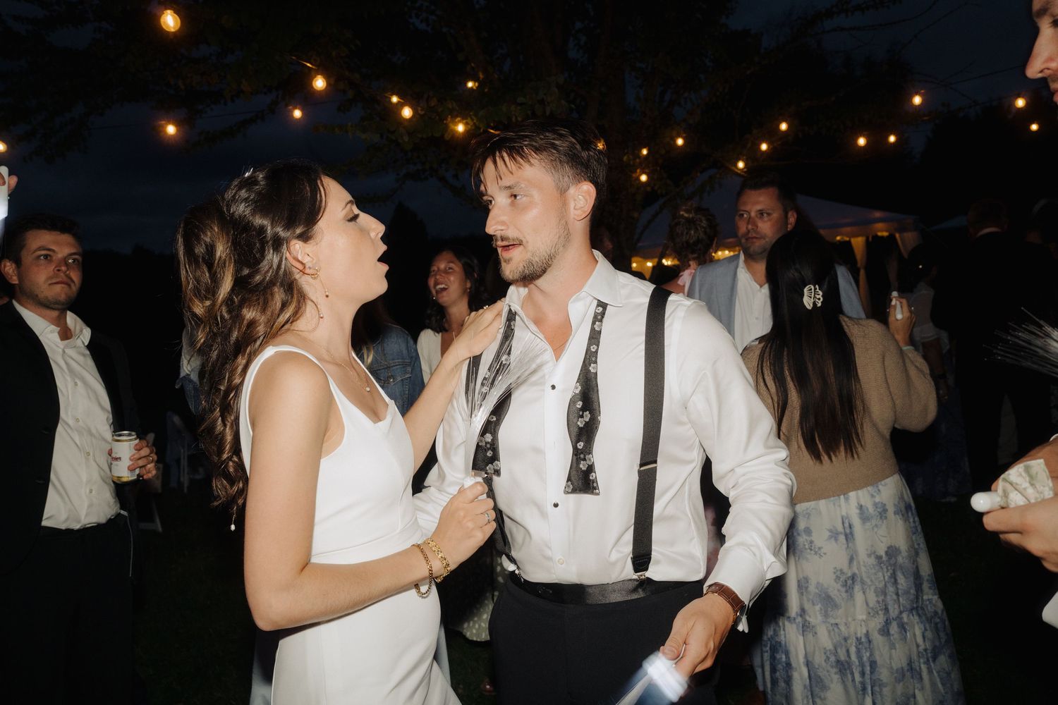 Wedding celebration at night with string lights creating a magical outdoor atmosphere.