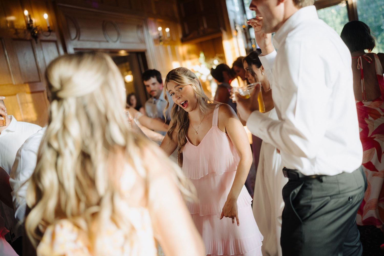 Wedding reception dance party with guests in pink dresses enjoying the celebration.