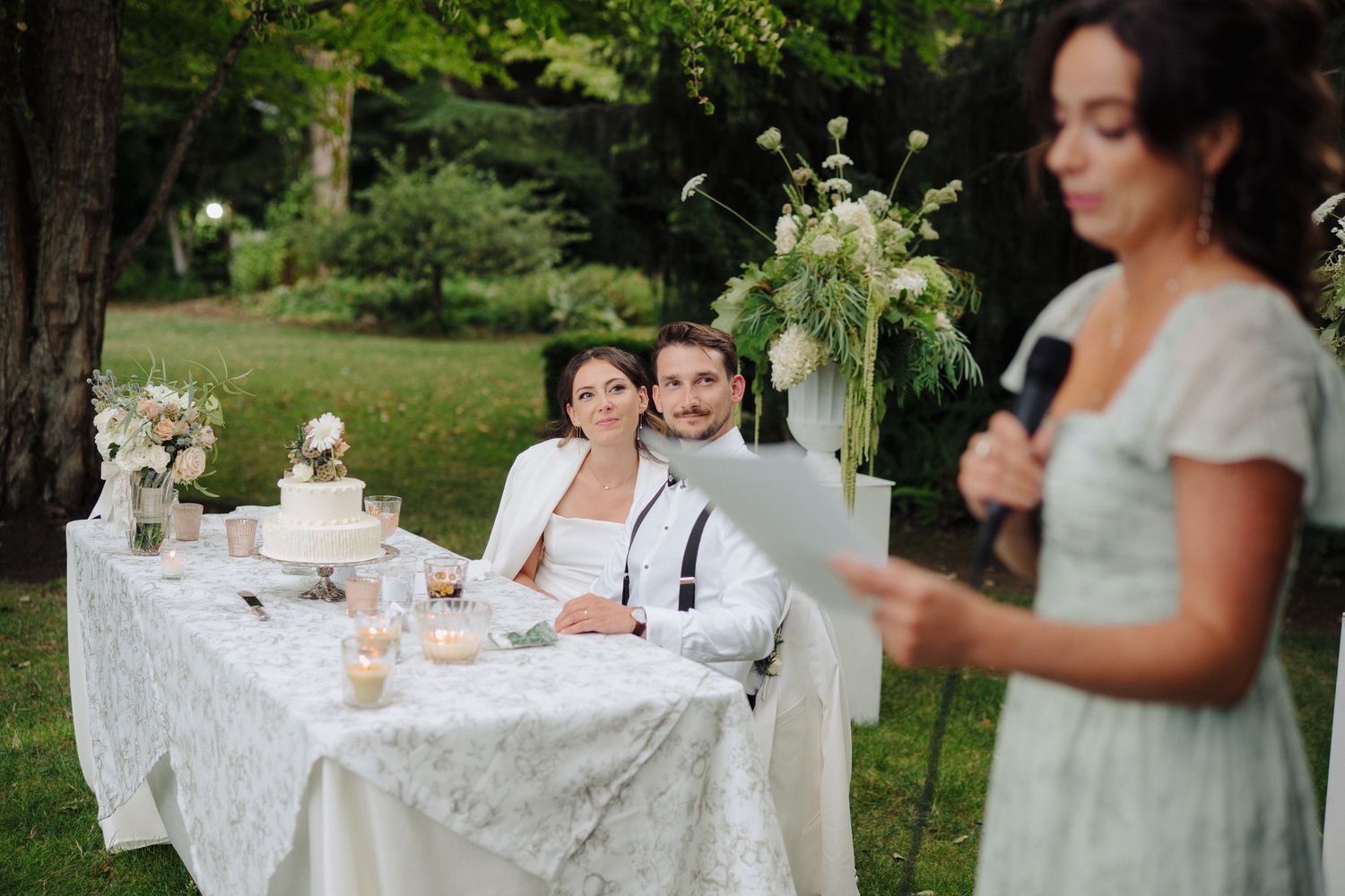 Wedding reception tables decorated with delicate lace tablecloths and floral centerpieces in an outdoor garden setting.