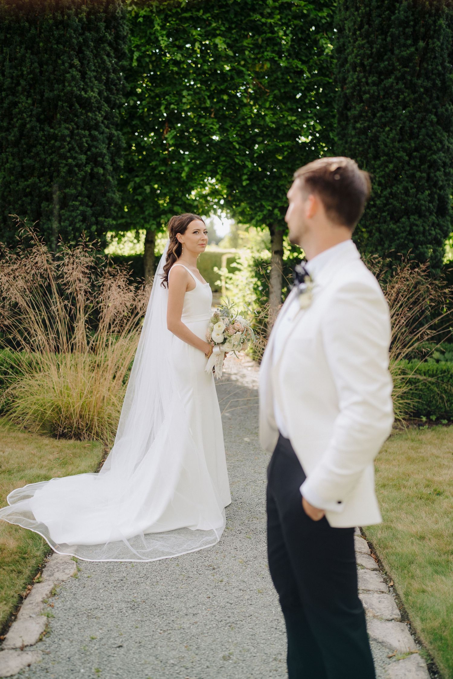 Couple dancing playfully on a garden path surrounded by greenery.