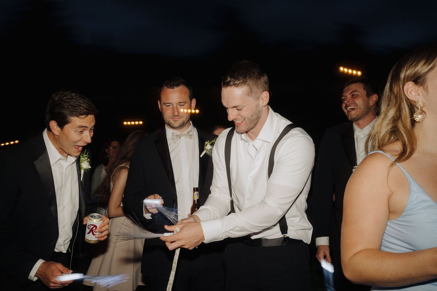 Wedding reception guests dancing and celebrating in a dimly lit venue.