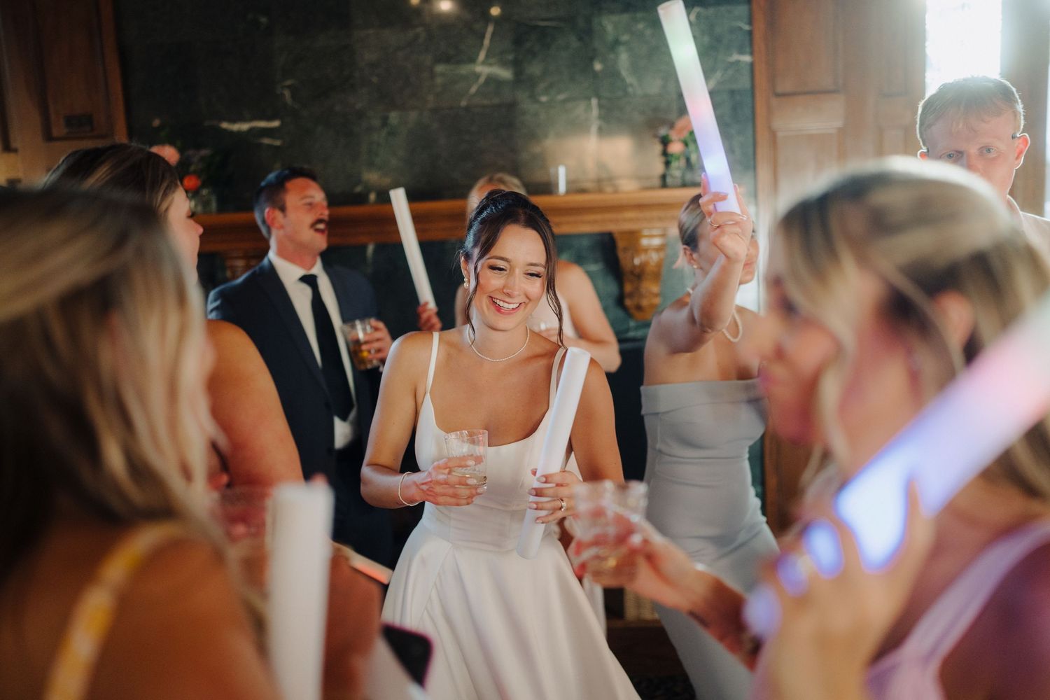 Wedding guests dancing and celebrating on a dance floor at an indoor reception venue.