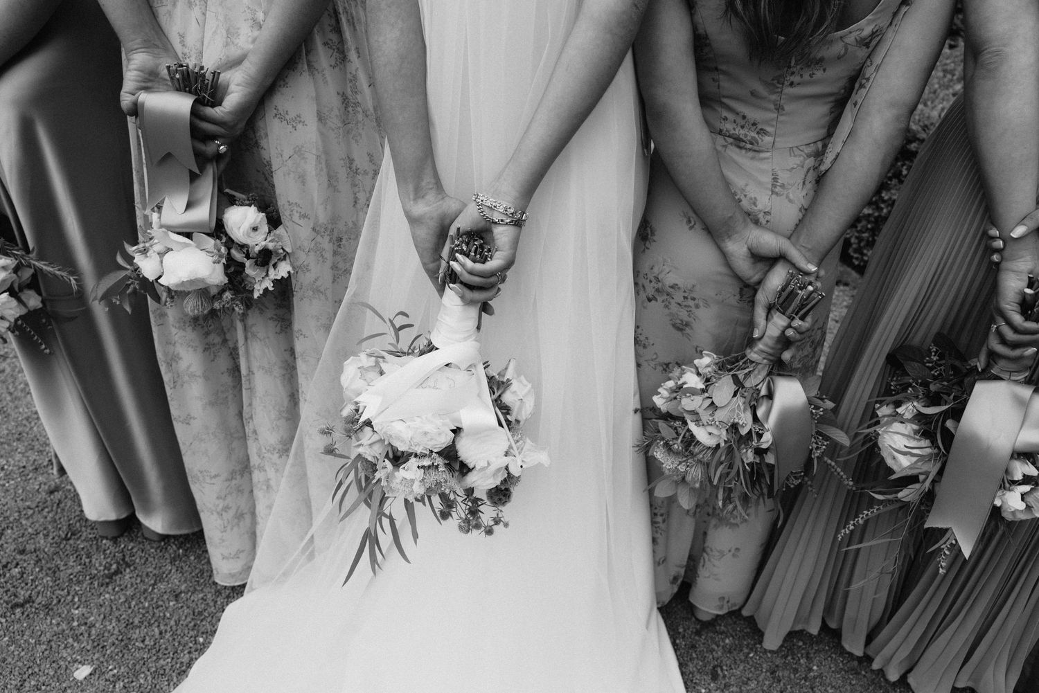 Black and white detail shot of wedding party formal attire and bouquets.