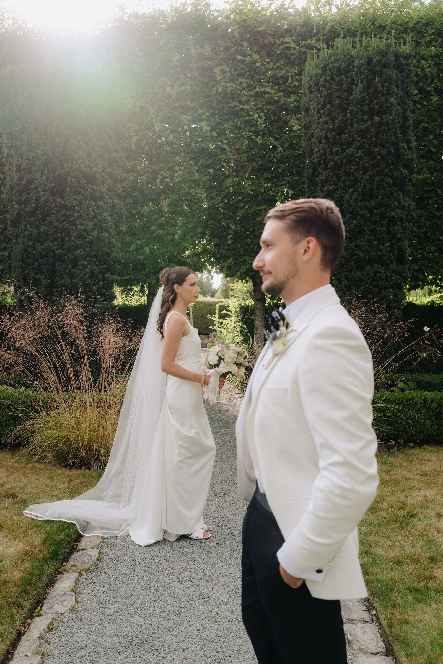 Wedding couple shares intimate moments in an outdoor garden setting with soft sunlight.