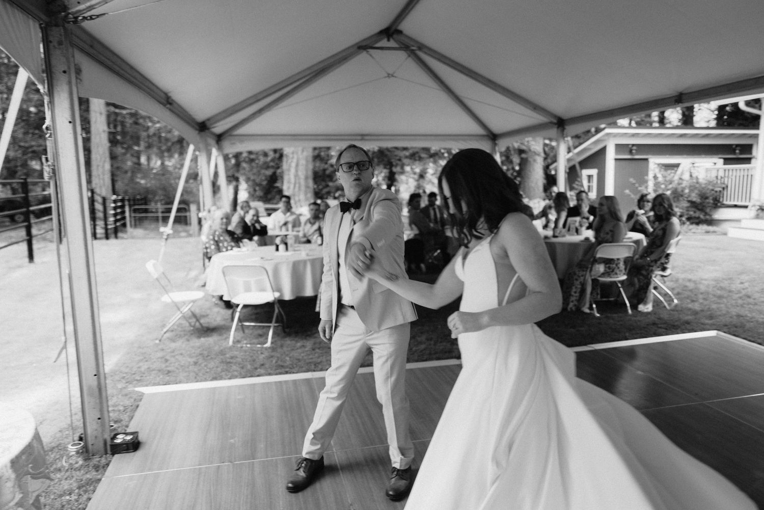 Wedding reception celebration under a white tent with dancing and festivities.